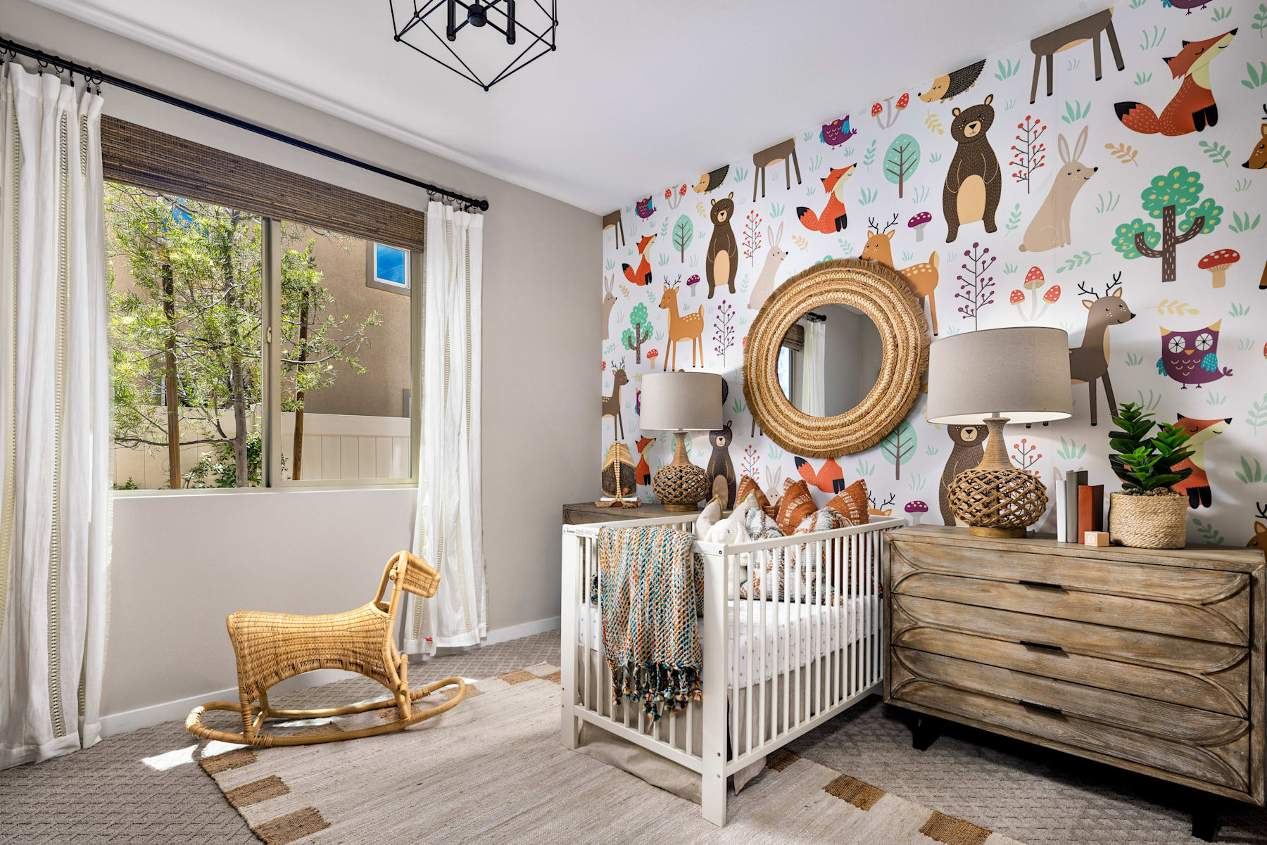 A cozy and whimsical nursery with a white crib, wooden dresser, and a rocking chair, surrounded by a vibrant wall mural featuring various woodland creatures and nature elements.