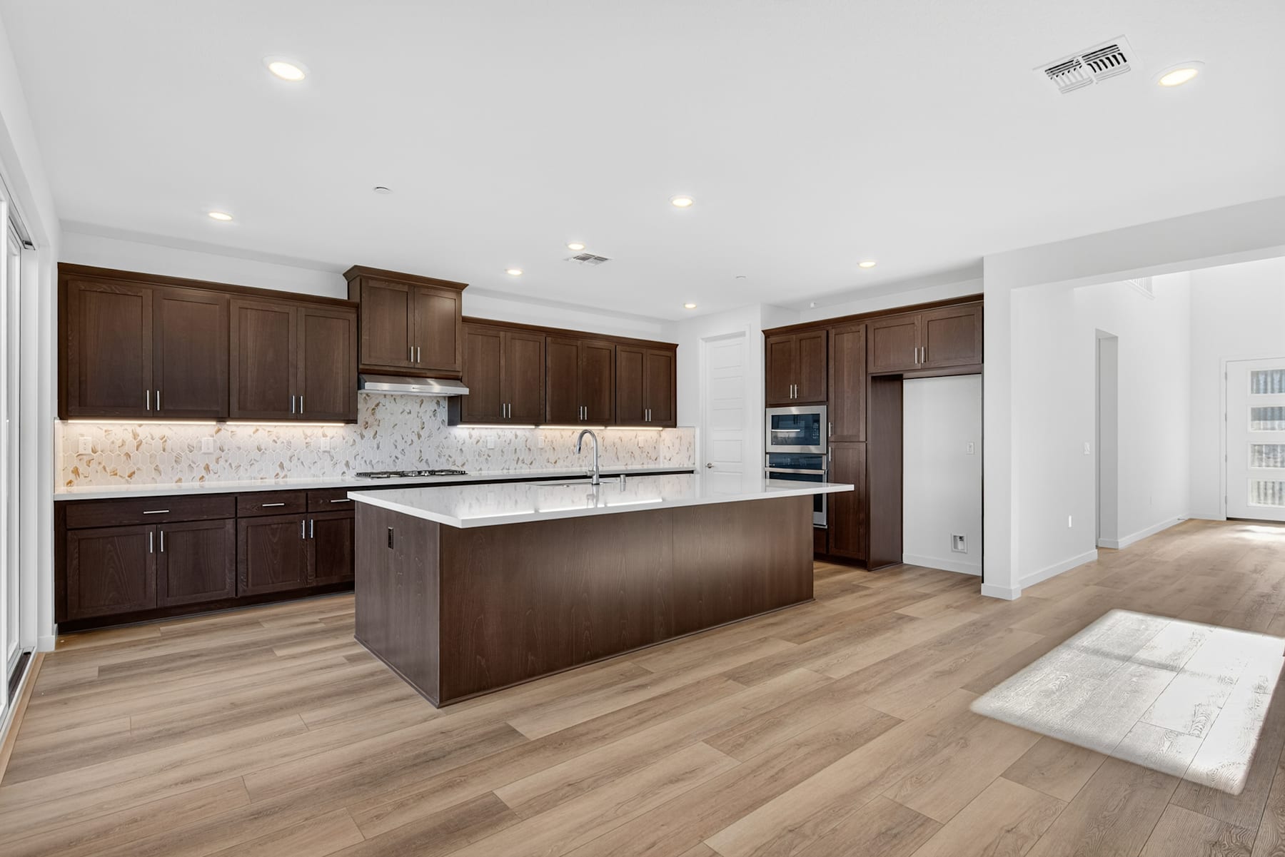 A modern, spacious kitchen with dark wood cabinets, a large island, and hardwood floors.