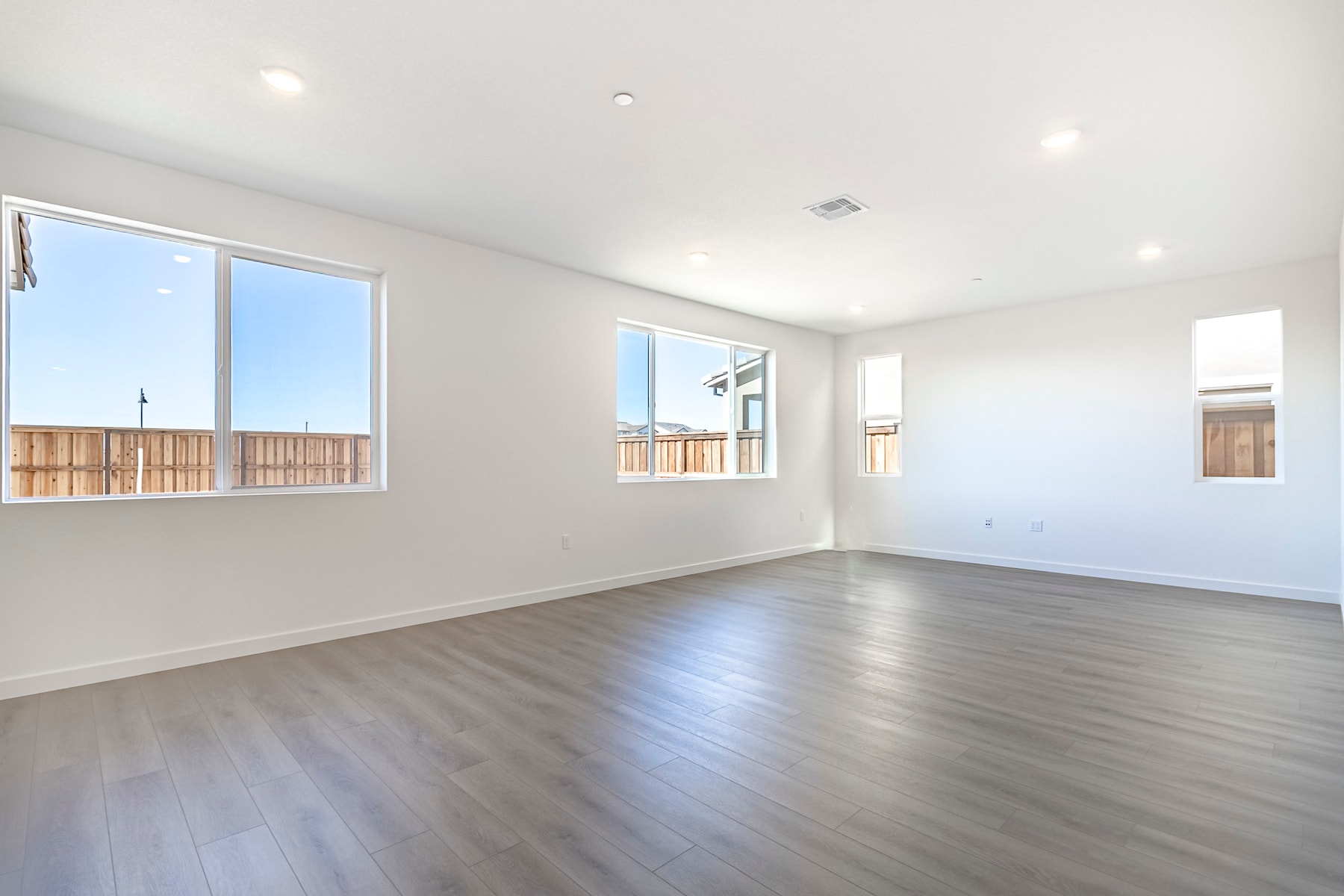 An empty, spacious room with large windows, hardwood floors, and a clean, minimalist design.