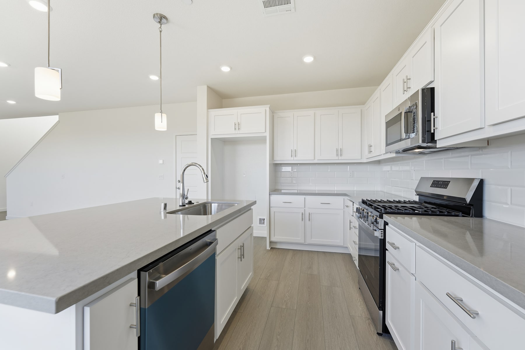 A modern, bright, and spacious kitchen with white cabinets, stainless steel appliances, and a sleek countertop.