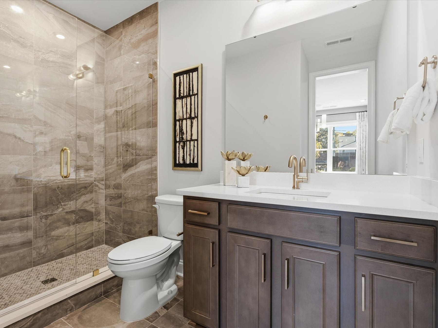 A modern and well-designed bathroom with a large vanity, a walk-in shower, and a neutral color scheme.