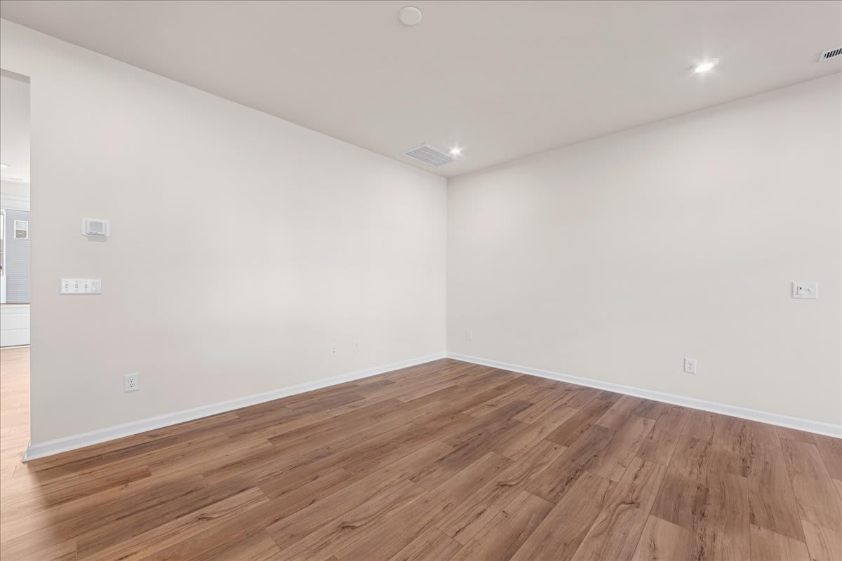 An empty room with white walls and a hardwood floor, creating a clean and minimalist atmosphere.
