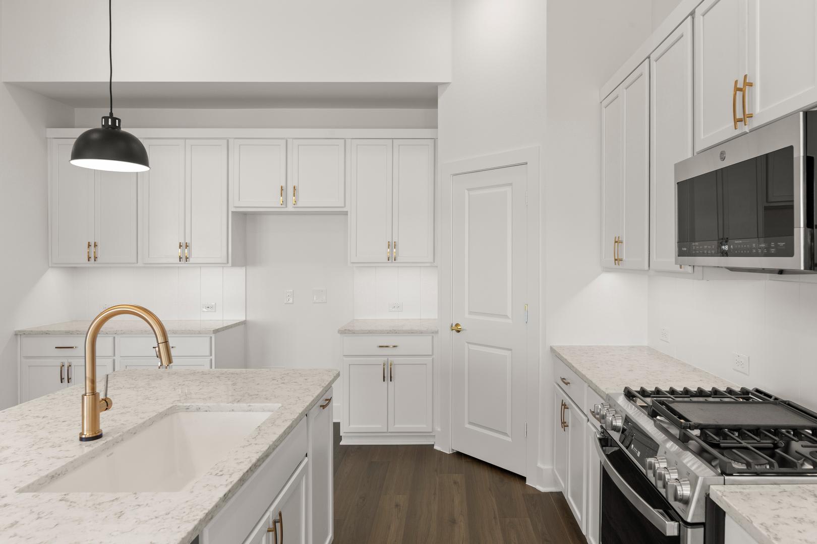 A modern, well-lit kitchen with white cabinets, a marble countertop, and a gas stove in the background.
