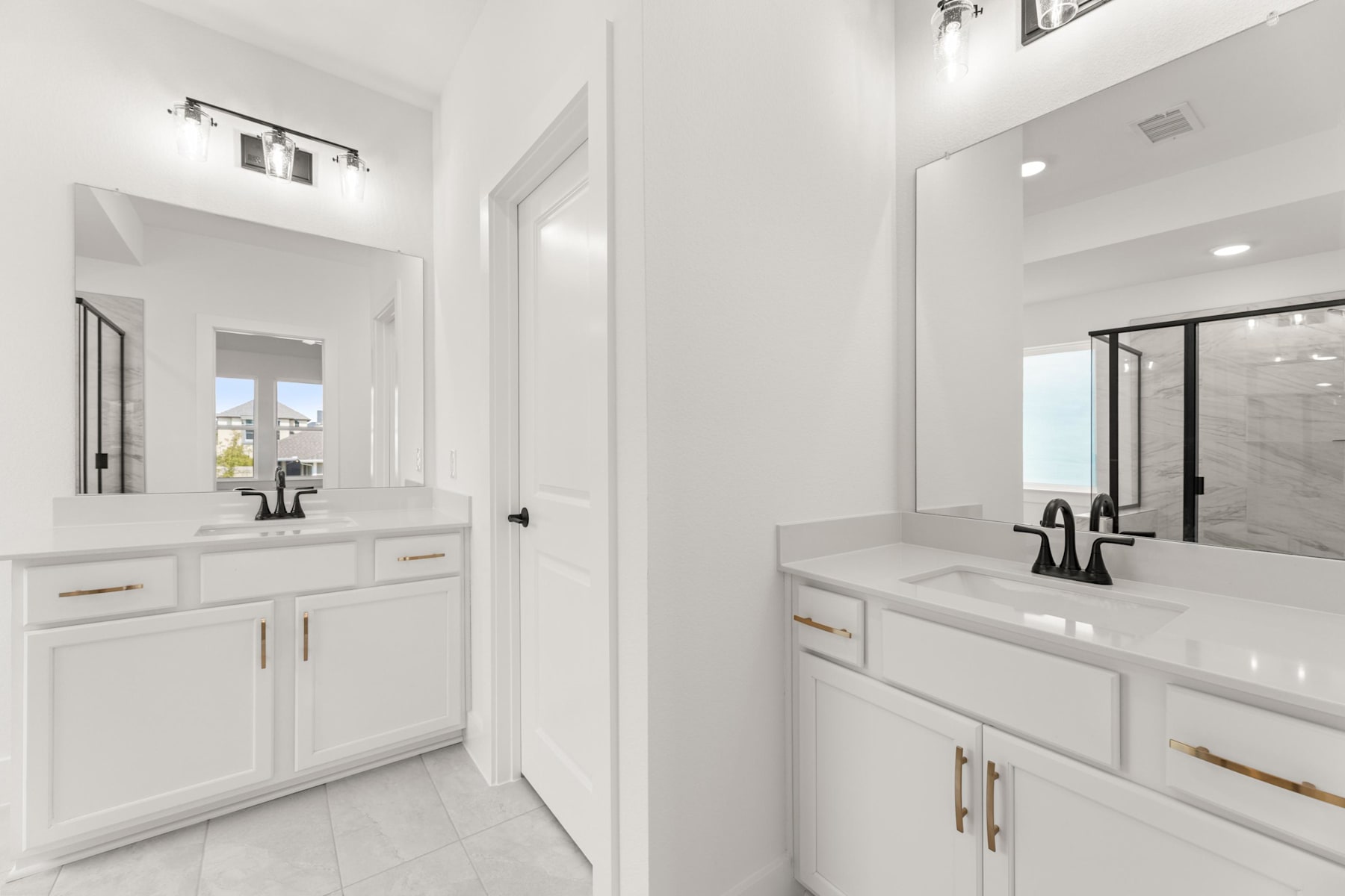 A bright, modern bathroom with white cabinets, countertops, and fixtures, featuring a double vanity and a large mirror.