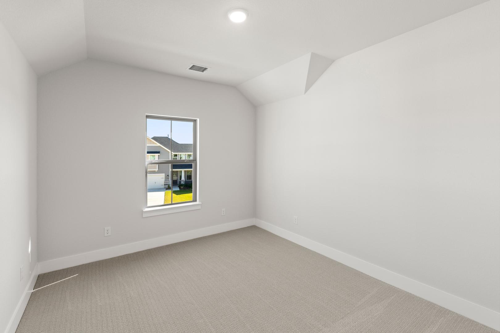A bright, minimalist room with a large window overlooking a residential neighborhood in the background.