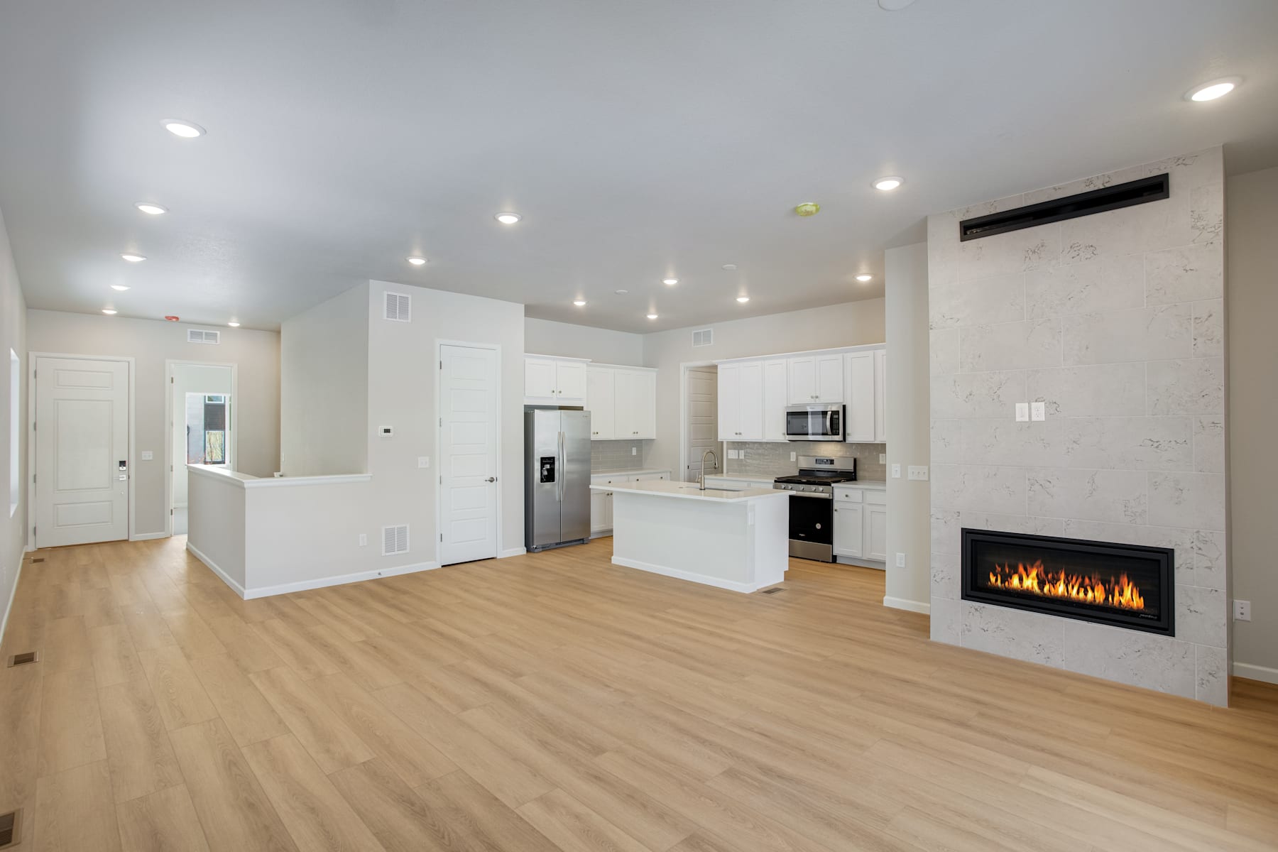 A modern, open-concept living space with a fireplace, kitchen, and hardwood floors, creating a bright and inviting atmosphere.