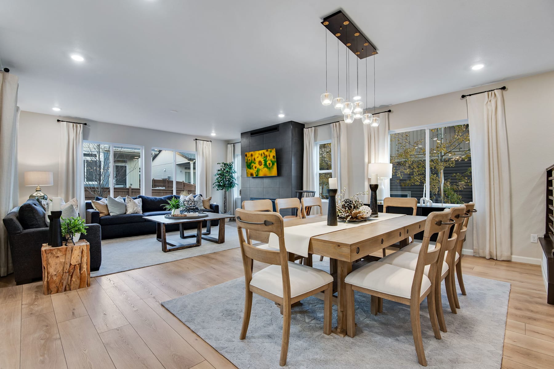 A modern and spacious living room with a dining area, featuring wooden furniture, a large abstract painting, and a cozy atmosphere.