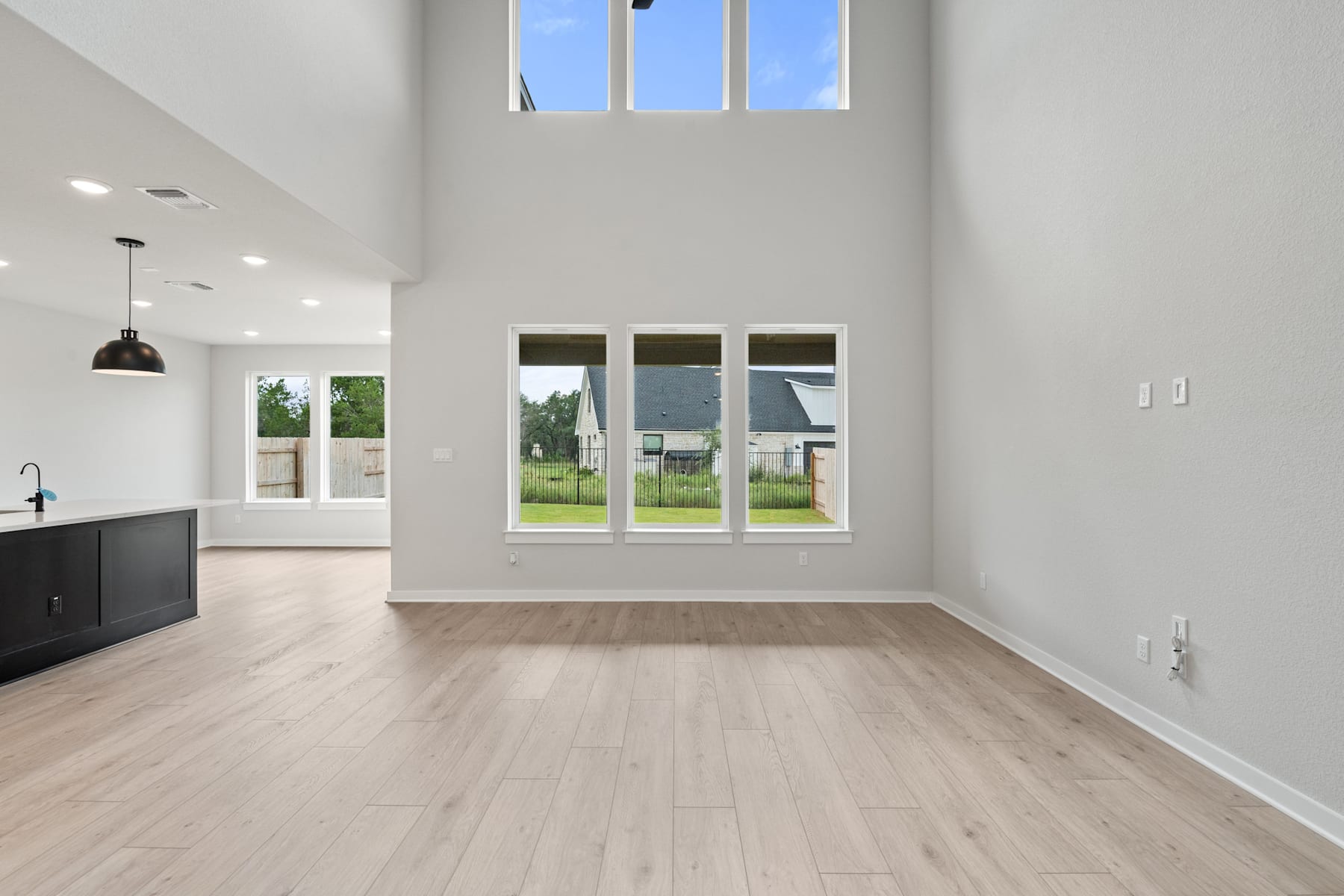 A spacious, bright room with high ceilings, large windows, and a hardwood floor. The room appears to be part of a modern, minimalist interior design.