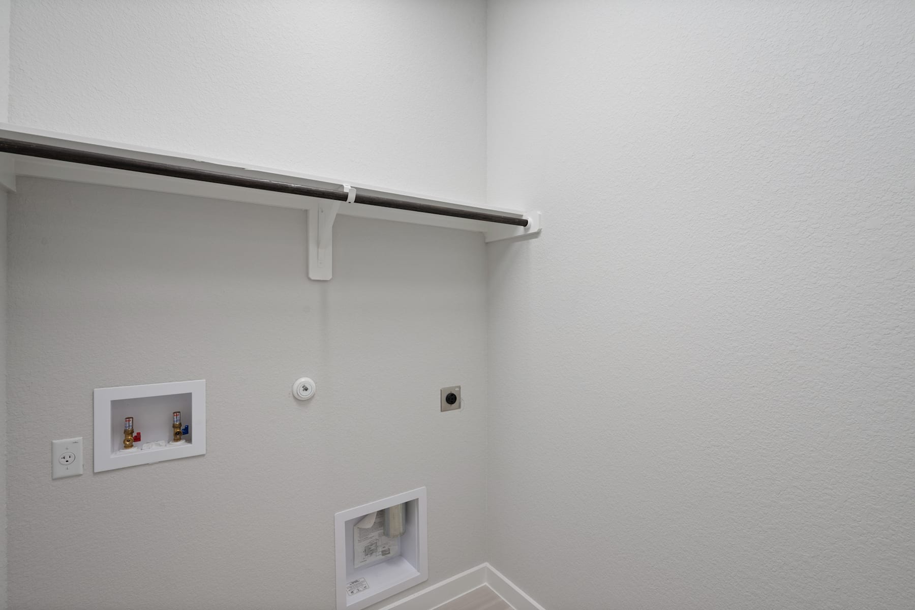 A minimalist, white-walled room with a closet rod and framed artwork on the wall.