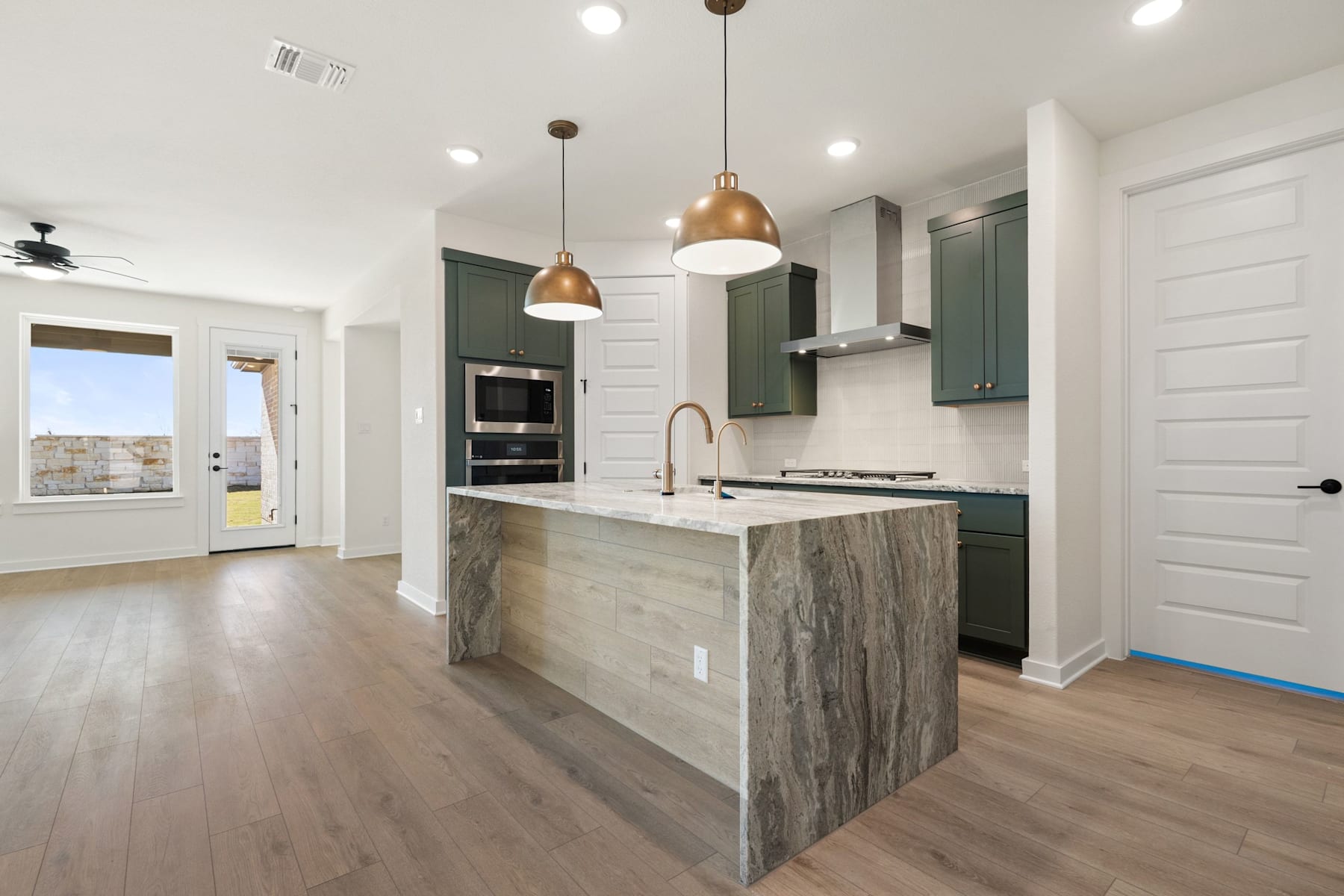 A modern, open-concept kitchen with a large island, pendant lighting, and a mix of light and dark cabinetry, set against a backdrop of a bright, airy space.