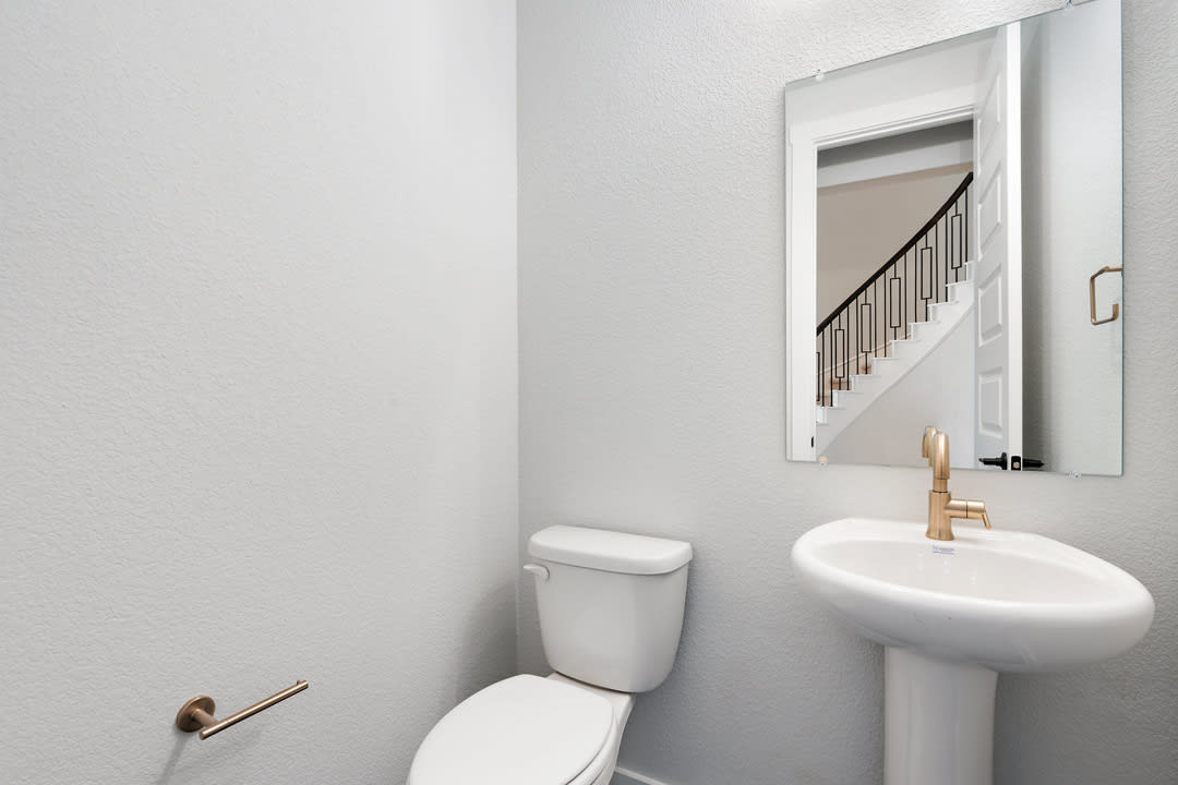 A simple and clean bathroom with a white toilet, sink, and mirror on the wall.