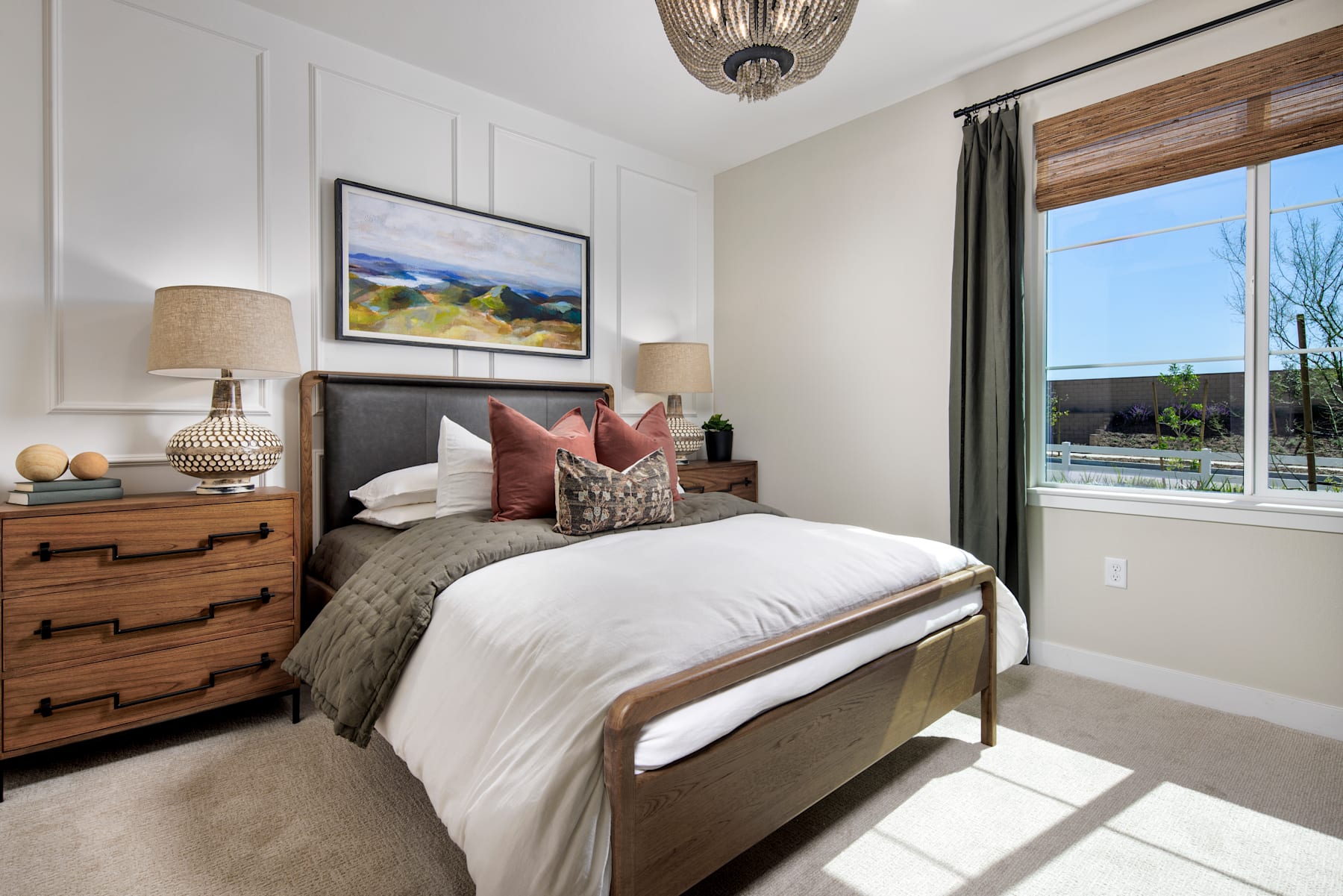 A cozy and inviting bedroom with a large bed, wooden furniture, and a framed landscape painting on the wall, overlooking a scenic outdoor view through the window.