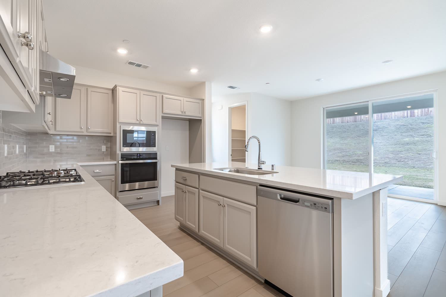 A modern, well-equipped kitchen with light-colored cabinets, stainless steel appliances, and a large window providing natural light.