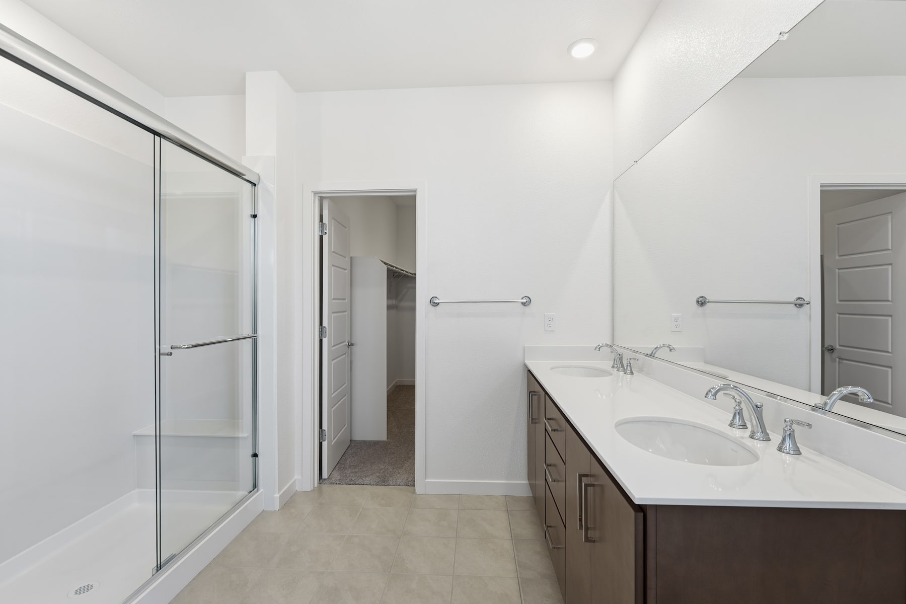 A modern, minimalist bathroom with a vanity, mirror, and glass shower enclosure, set against a bright, white background.
