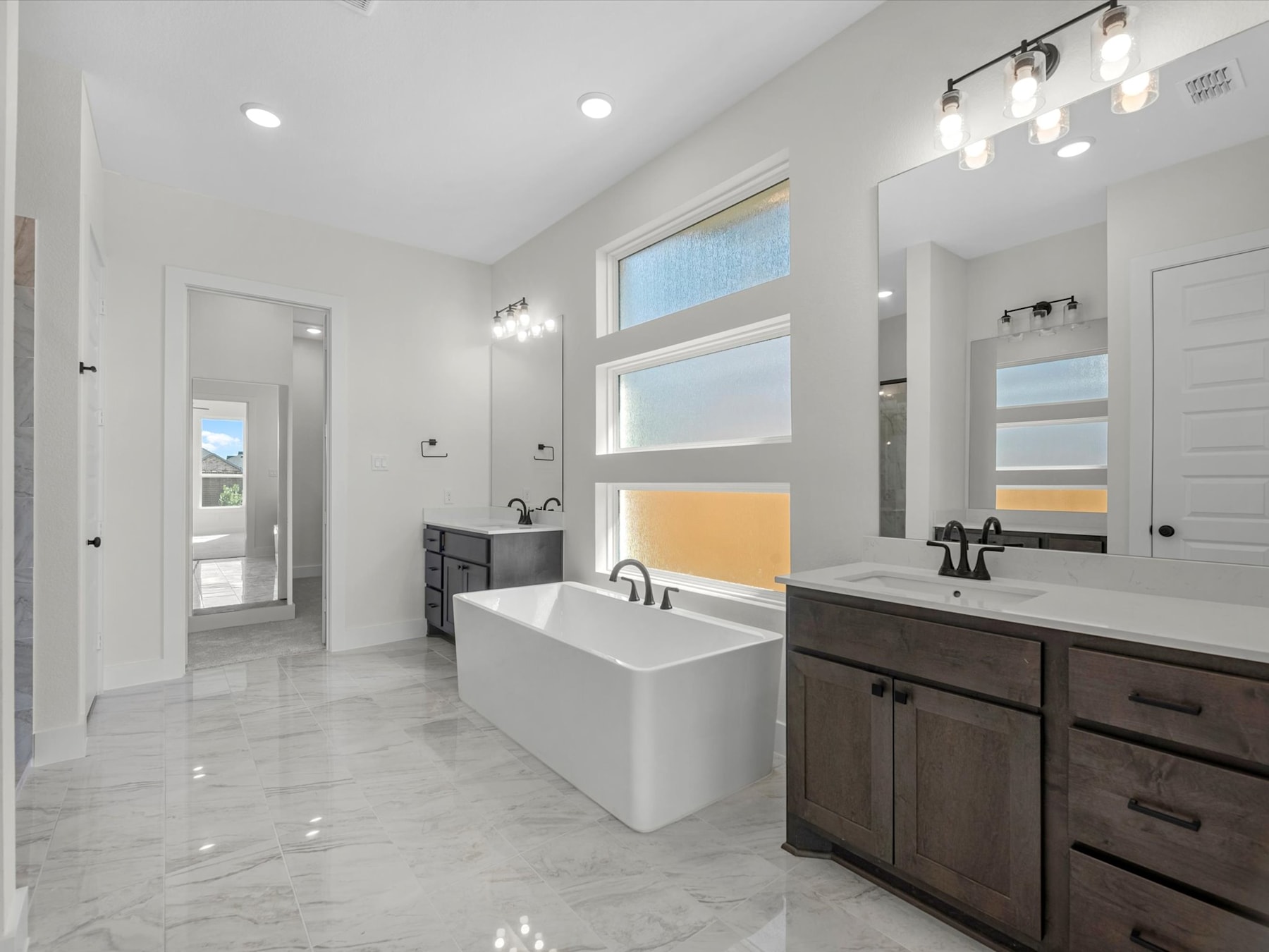 A modern and spacious bathroom with a freestanding bathtub, double vanity, and large window providing natural light.