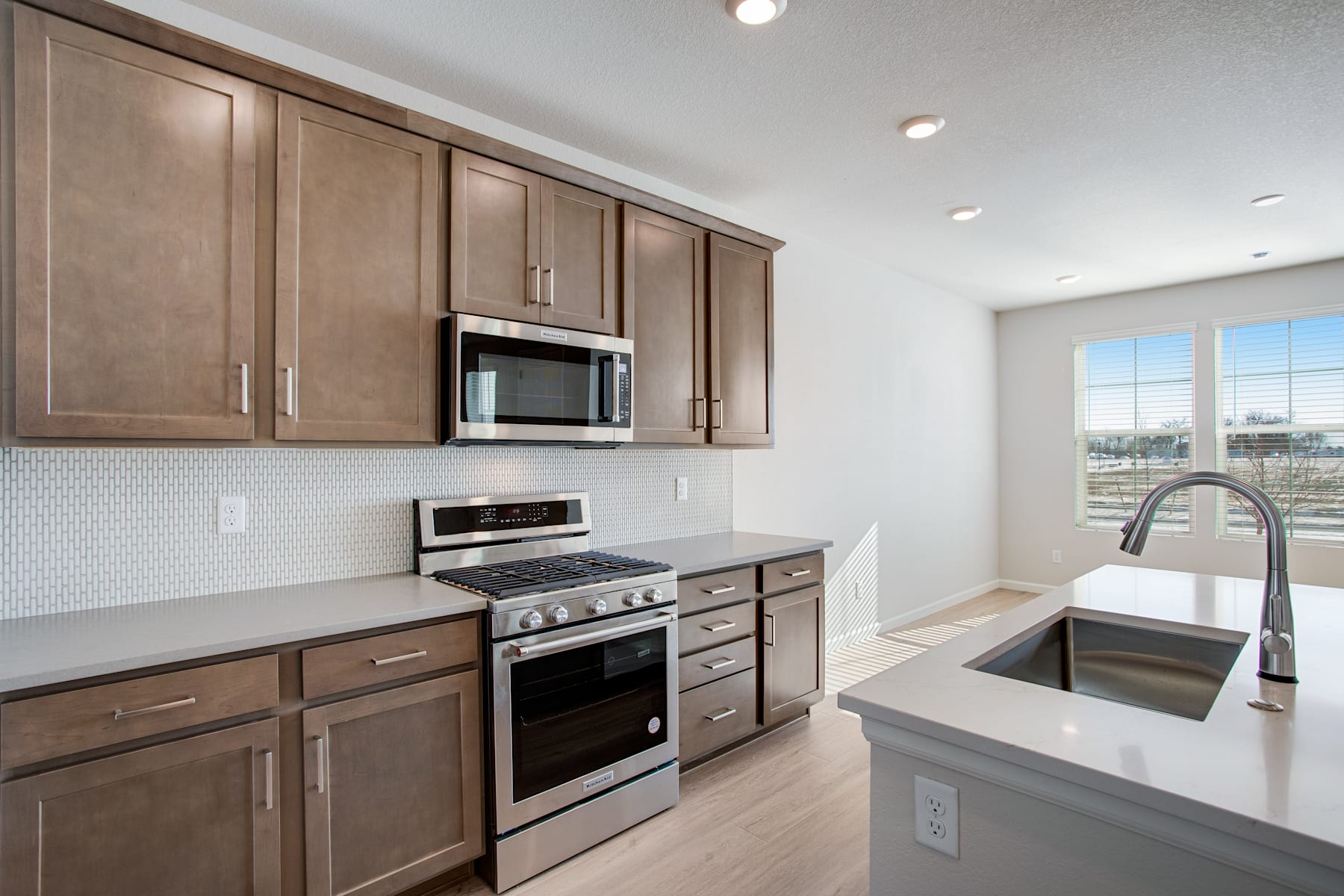 A modern, well-equipped kitchen with dark wood cabinets, stainless steel appliances, and a large window providing natural light.