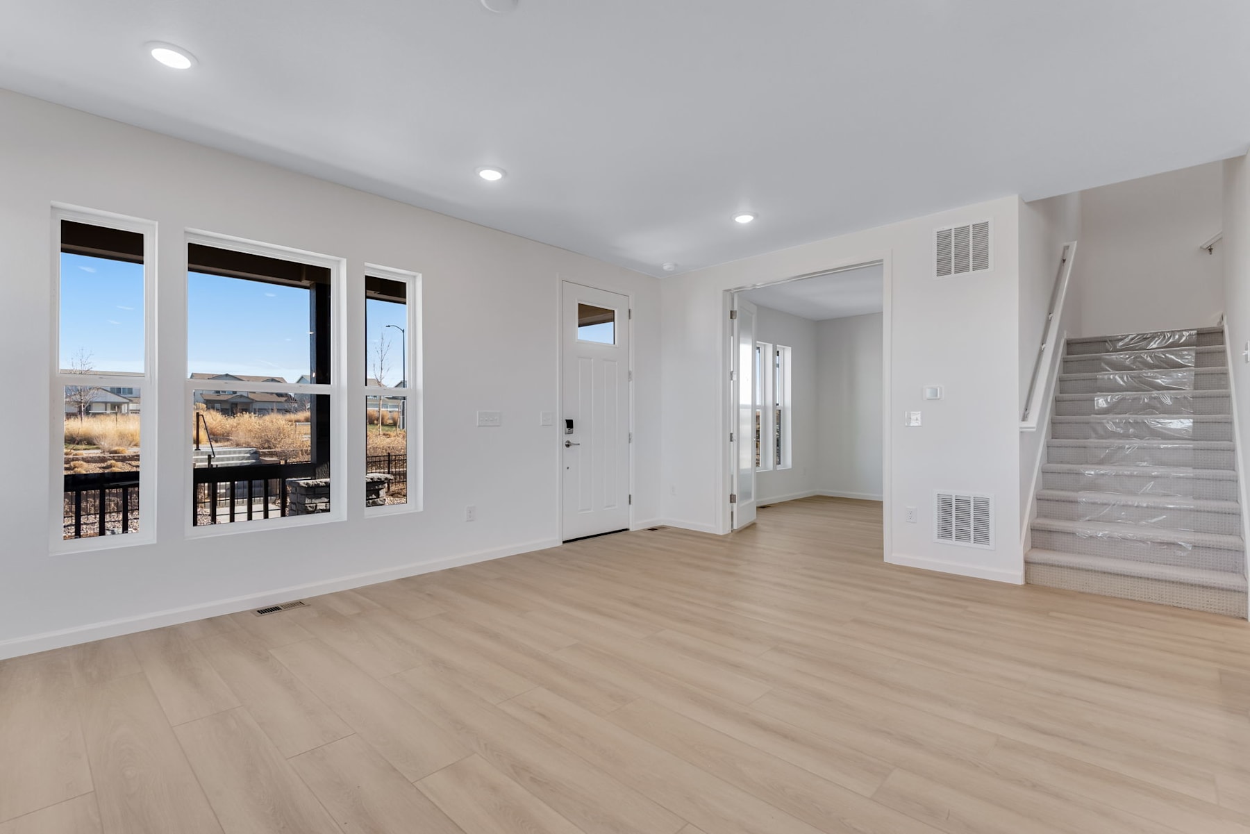 A spacious, well-lit room with large windows overlooking a scenic outdoor landscape, featuring hardwood floors and a minimalist, modern design.
