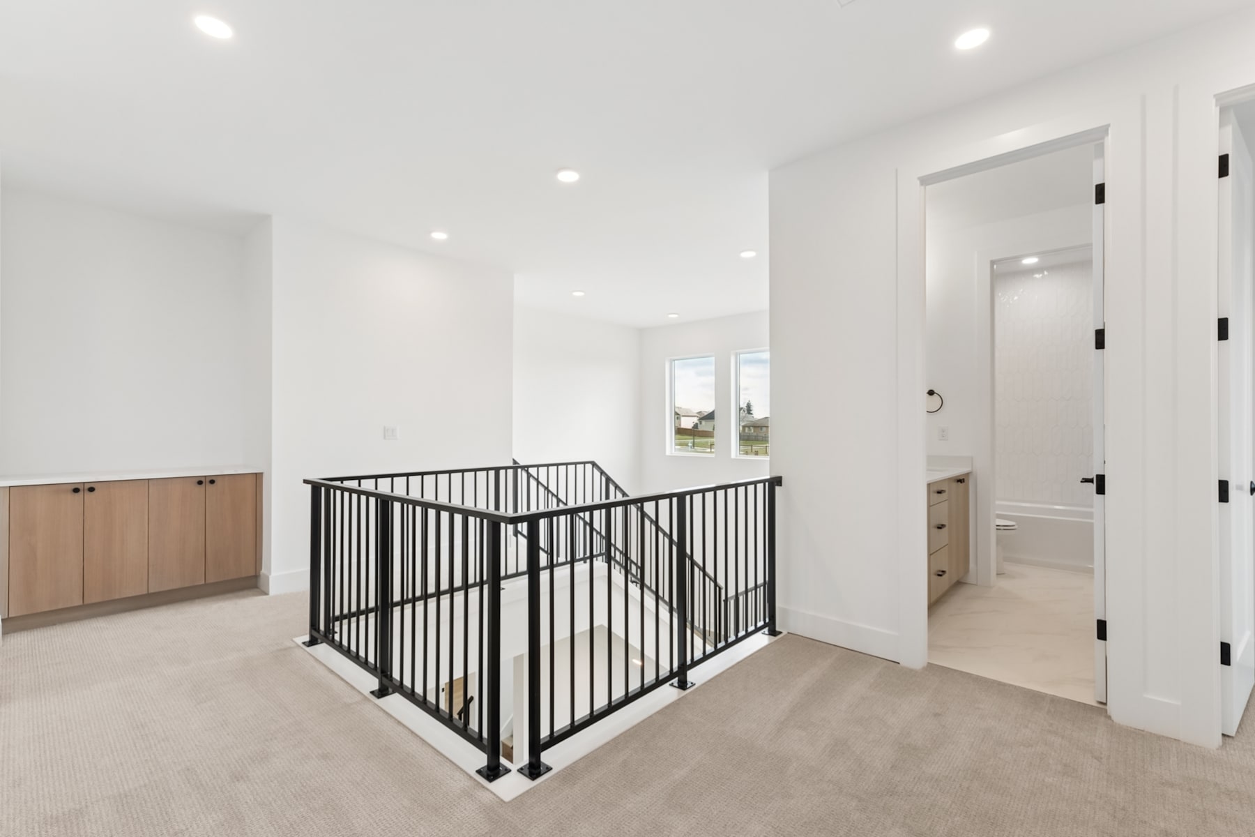 A bright and spacious interior with a metal railing dividing the room, leading to a doorway in the background.