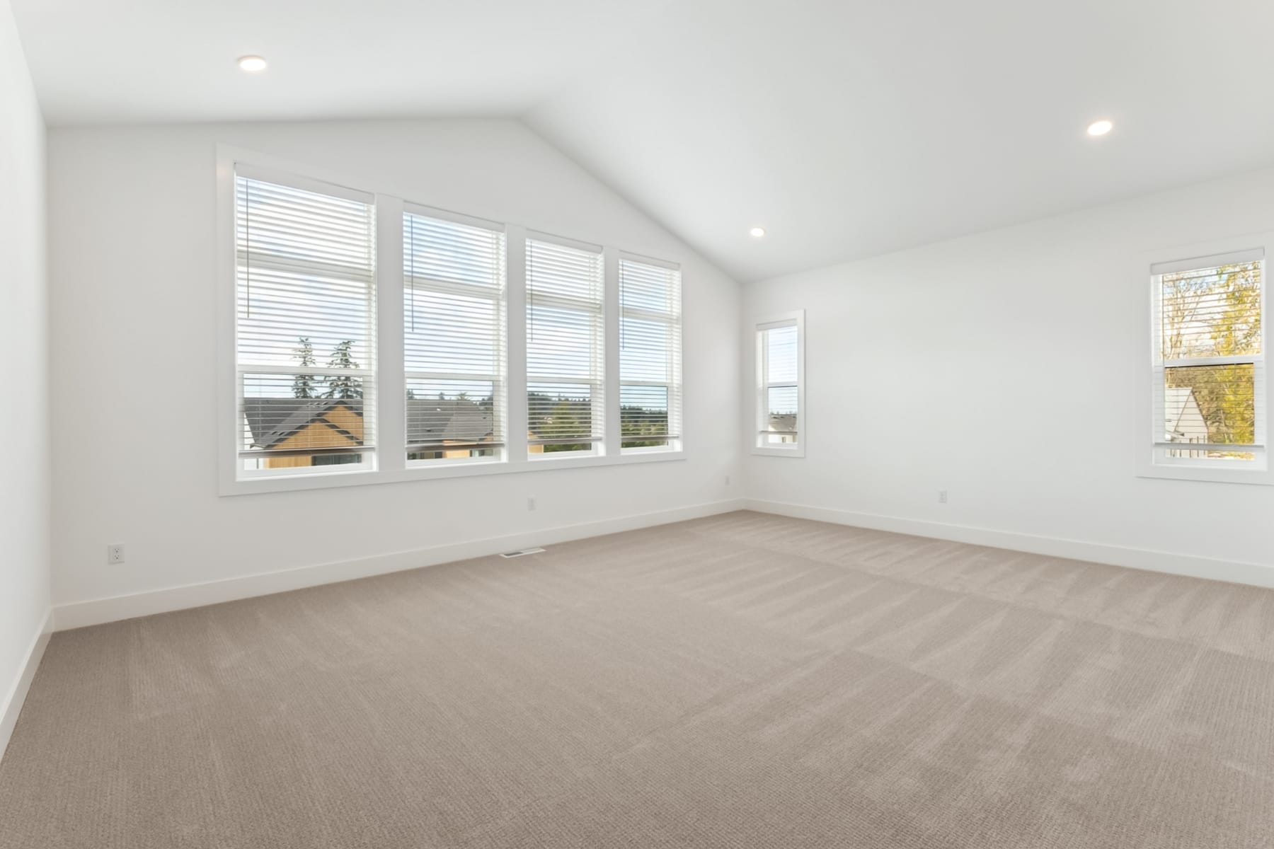 A bright and spacious room with large windows, a neutral-colored floor, and a clean, minimalist aesthetic.