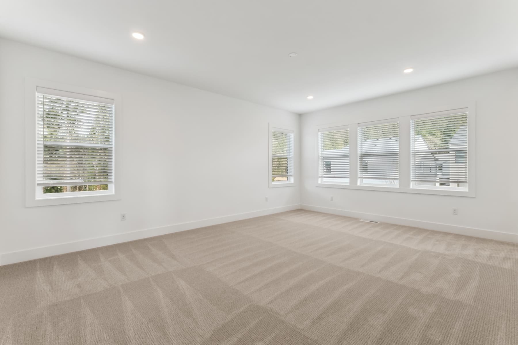 A bright, spacious room with large windows, hardwood floors, and a clean, minimalist design.