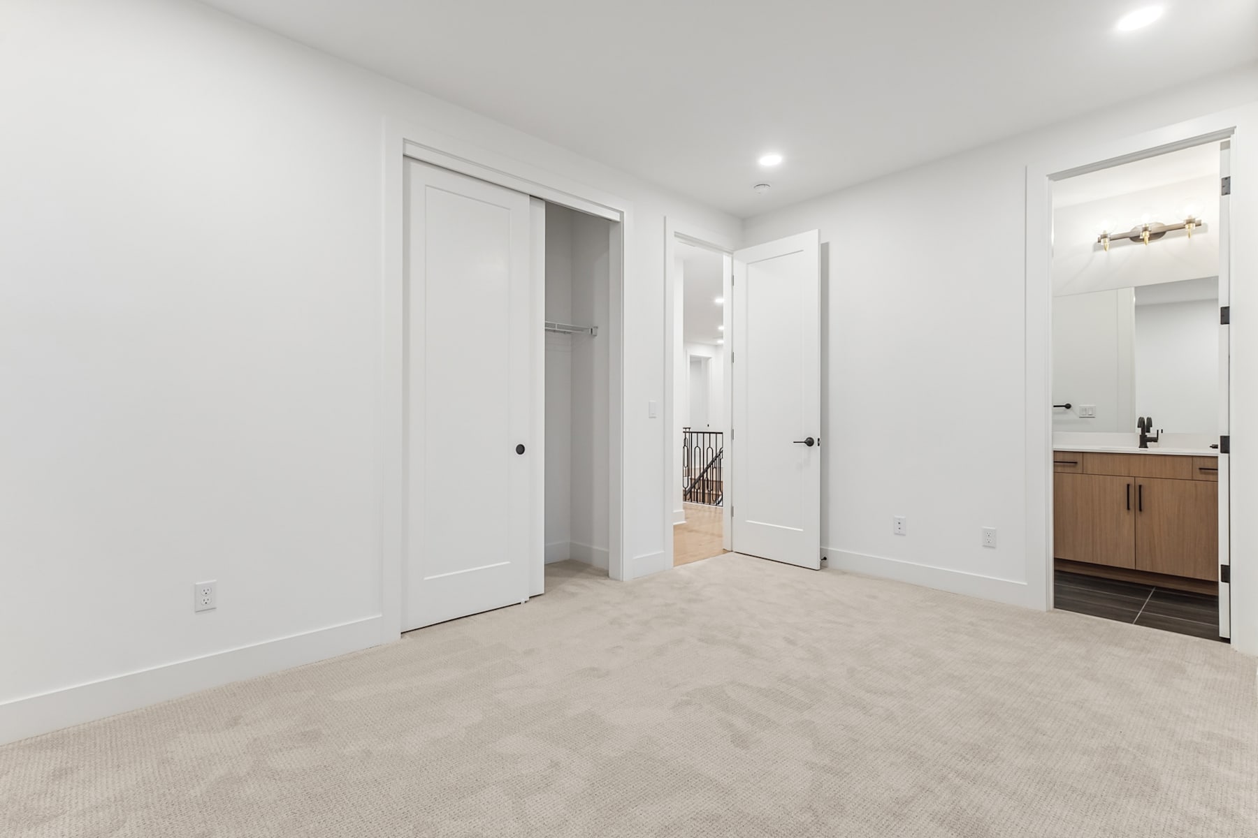 A spacious, minimalist room with white walls, light-colored flooring, and a wooden cabinet visible in the background.