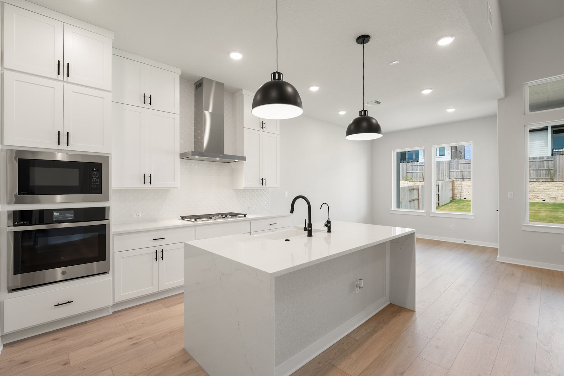 A modern, bright, and spacious kitchen with white cabinets, a central island, and pendant lighting fixtures.