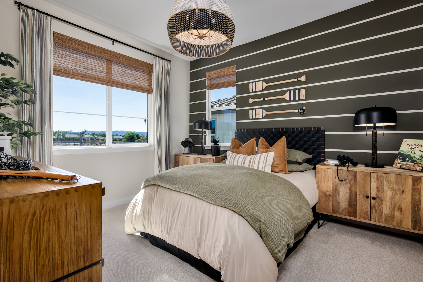 A cozy and modern bedroom with a wooden headboard, a pendant light fixture, and a scenic view through the window.