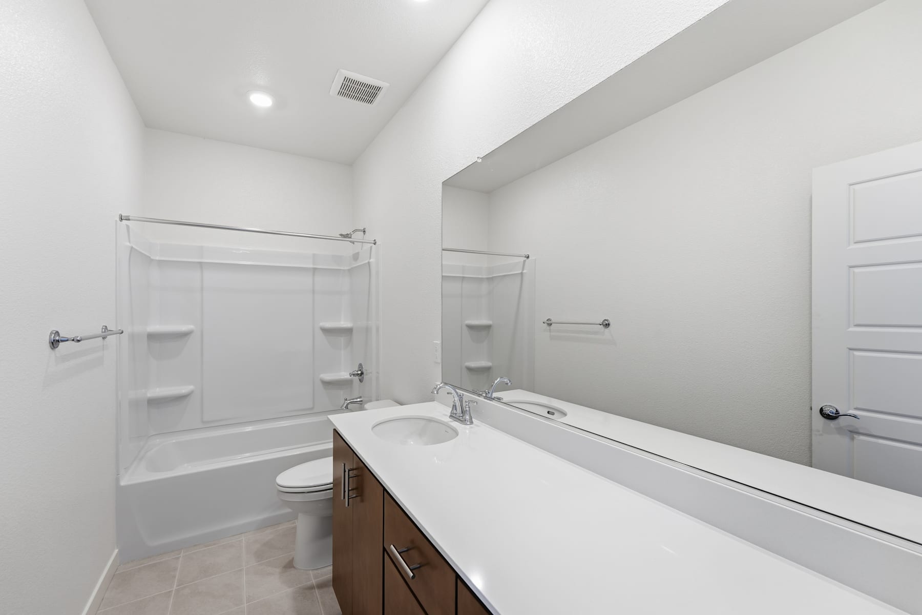A modern, minimalist bathroom with a white vanity, tiled floor, and a shower enclosure visible in the background.
