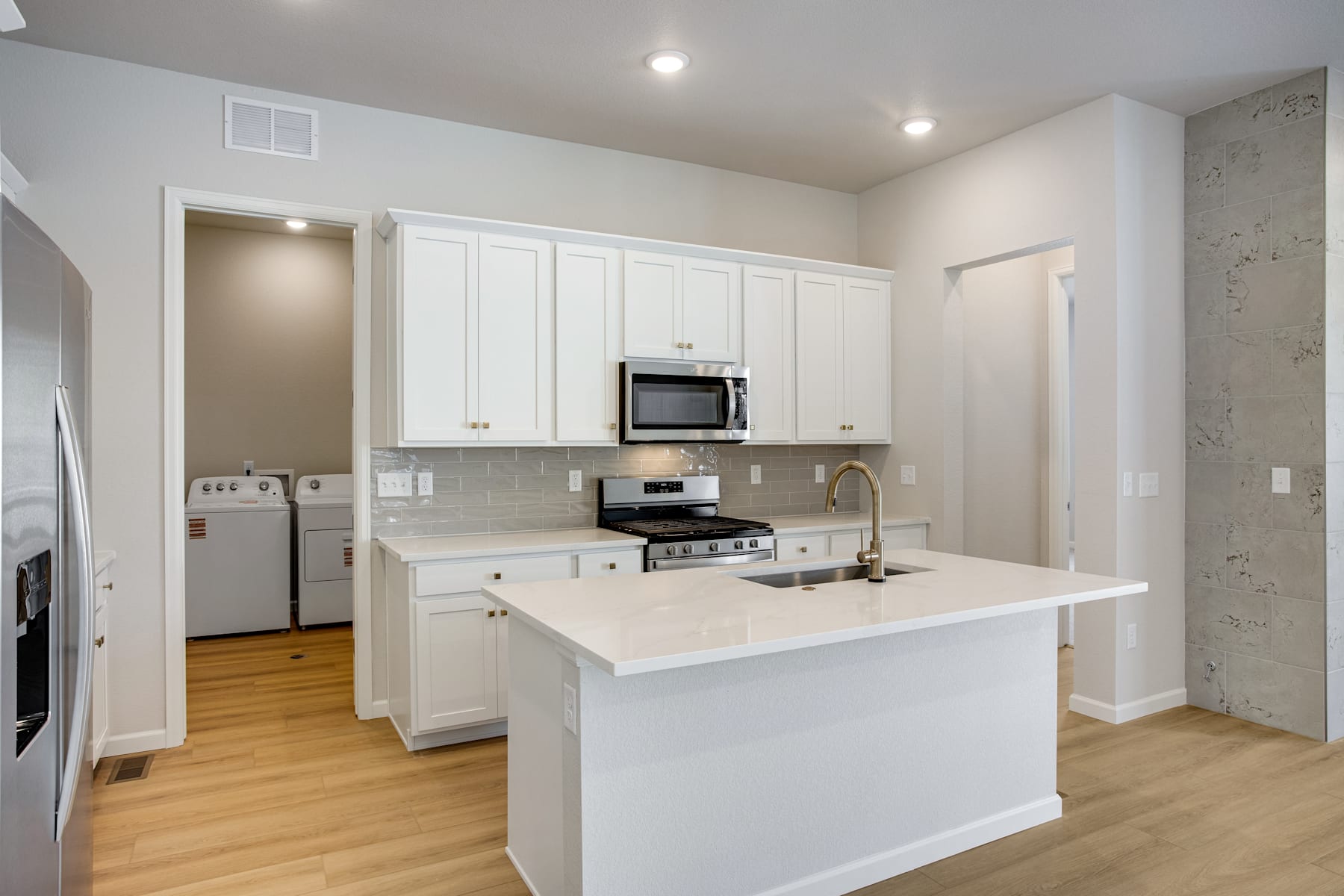 A modern, bright kitchen with white cabinets, a white countertop, and a stove and microwave visible in the background.