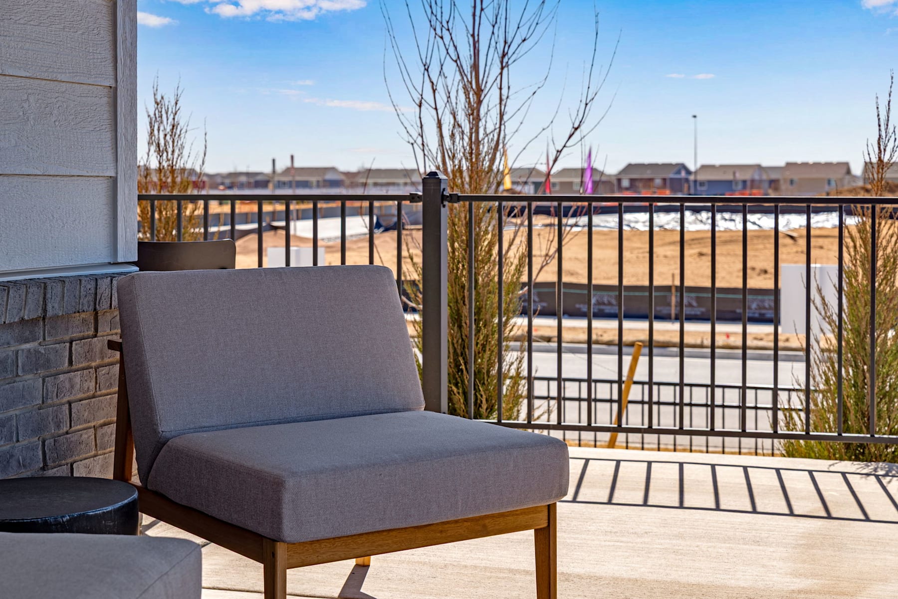 A cozy outdoor seating area on a balcony, with a view of a cityscape in the background and bare trees in the foreground.