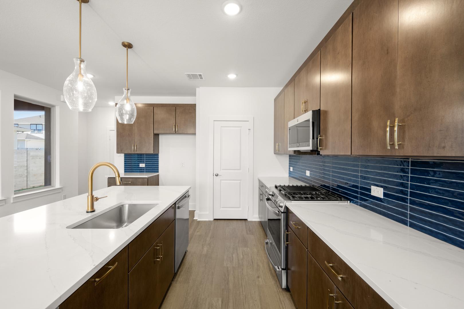A modern and stylish kitchen with dark wood cabinets, white countertops, and pendant lighting fixtures, set against a bright and airy background.