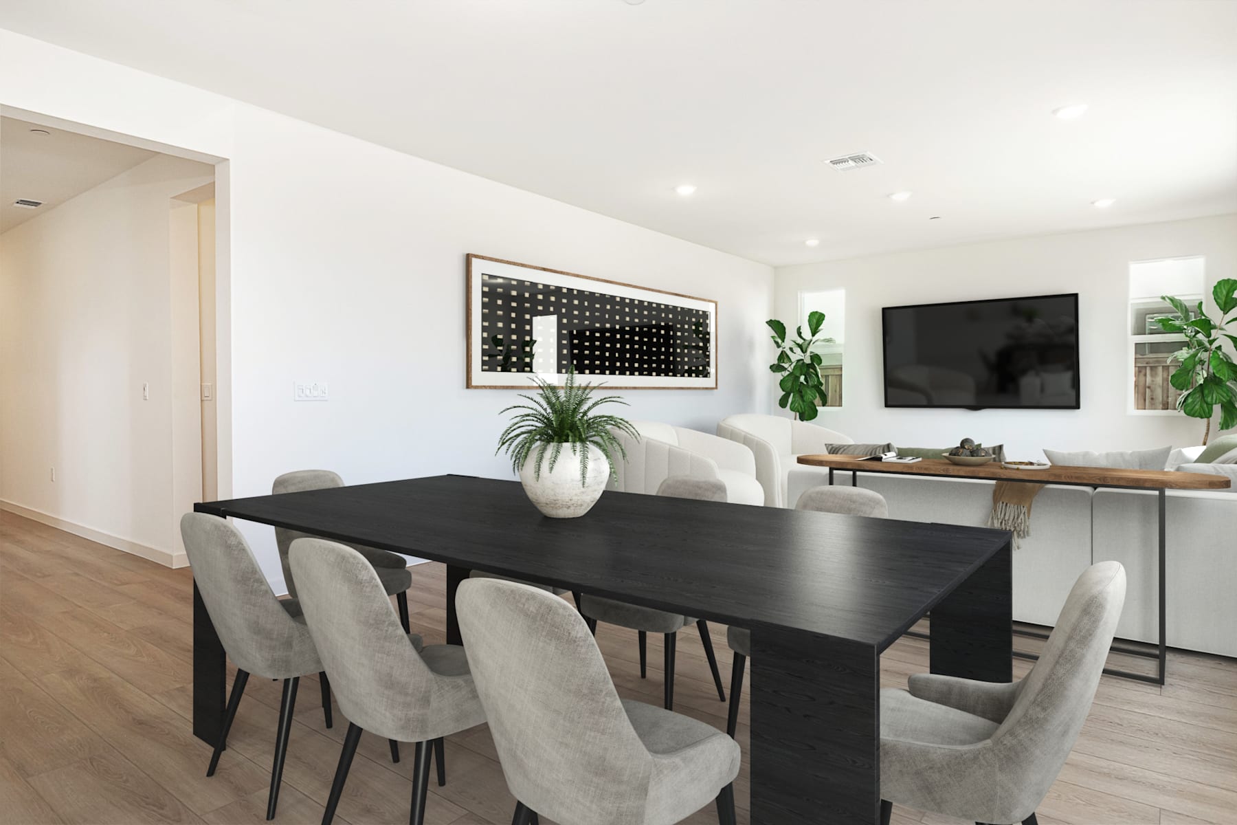 A modern and minimalist dining room with a dark wooden table surrounded by gray upholstered chairs, a large wall art piece, and a television mounted on the wall in the background.