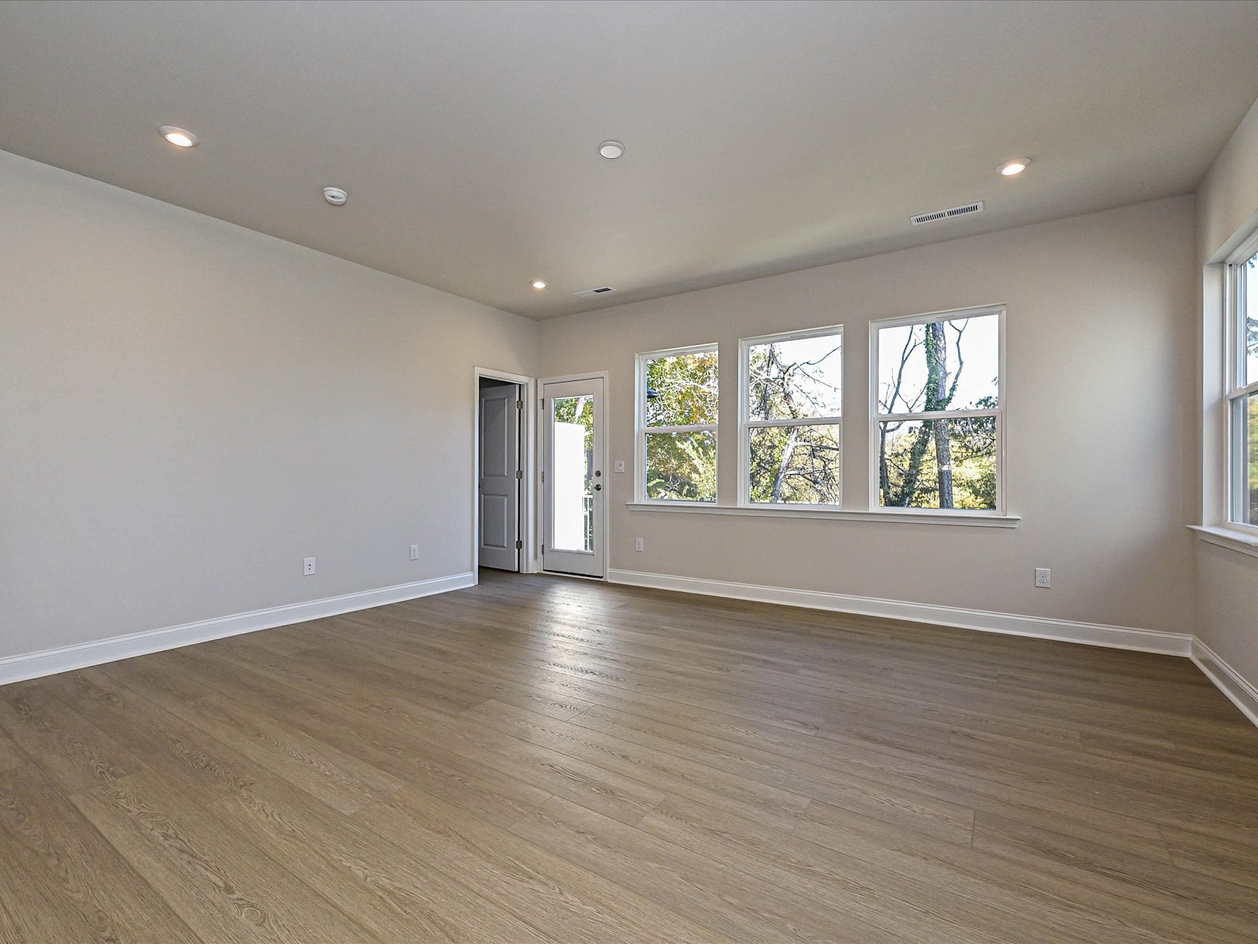 A spacious, well-lit room with hardwood floors, large windows, and recessed lighting, providing a bright and airy atmosphere.