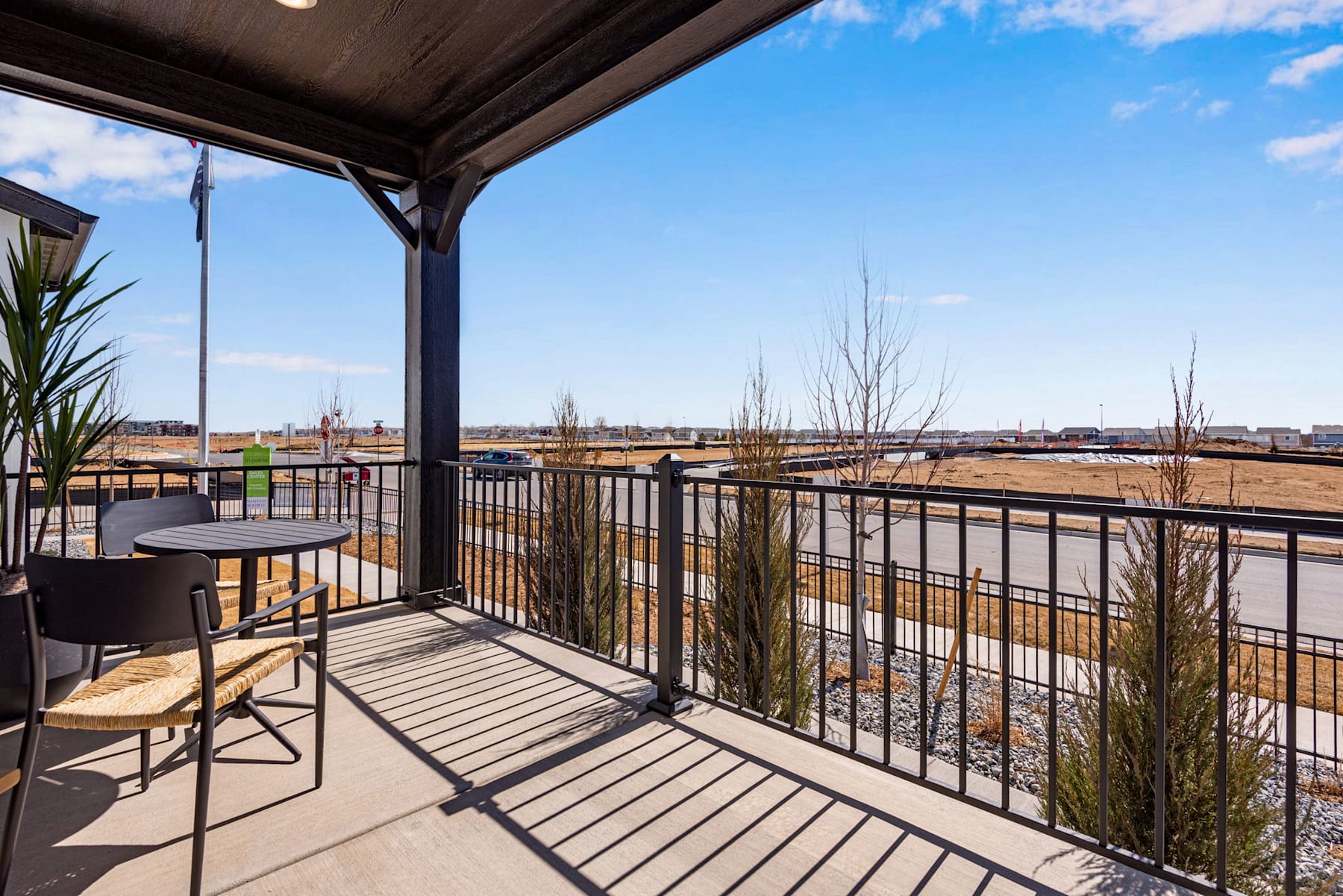 A covered balcony overlooking a scenic urban landscape with buildings, trees, and a clear blue sky in the background.
