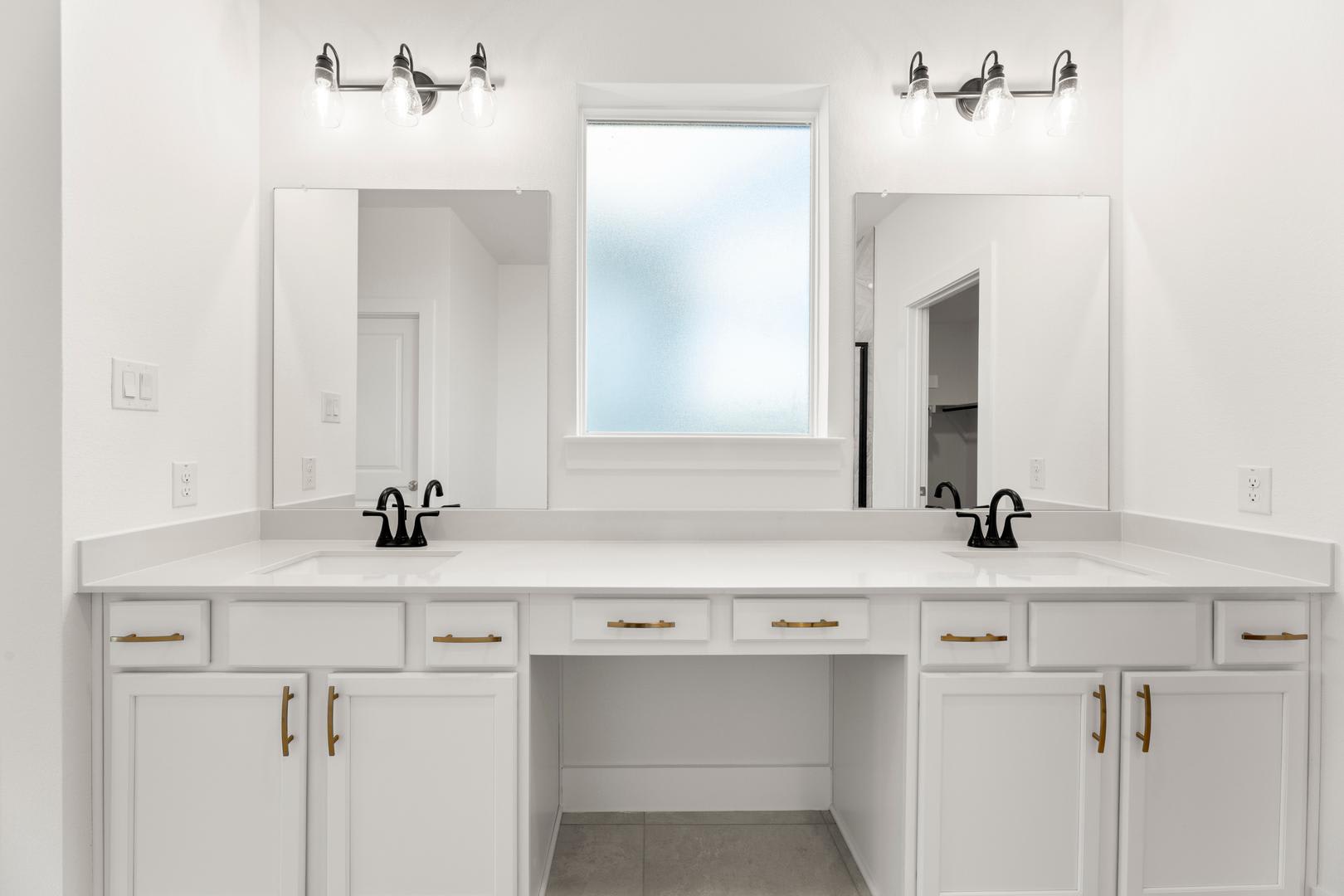 A modern, white bathroom vanity with two sinks, mirrors, and wall sconces, set against a bright, minimalist background.
