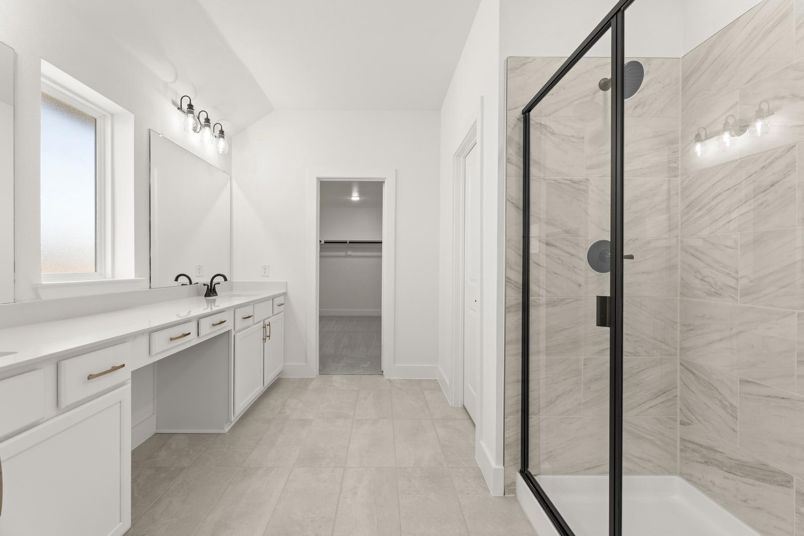A modern, minimalist bathroom with white cabinets, a marble-like countertop, and a glass-enclosed shower area, creating a clean and spacious atmosphere.