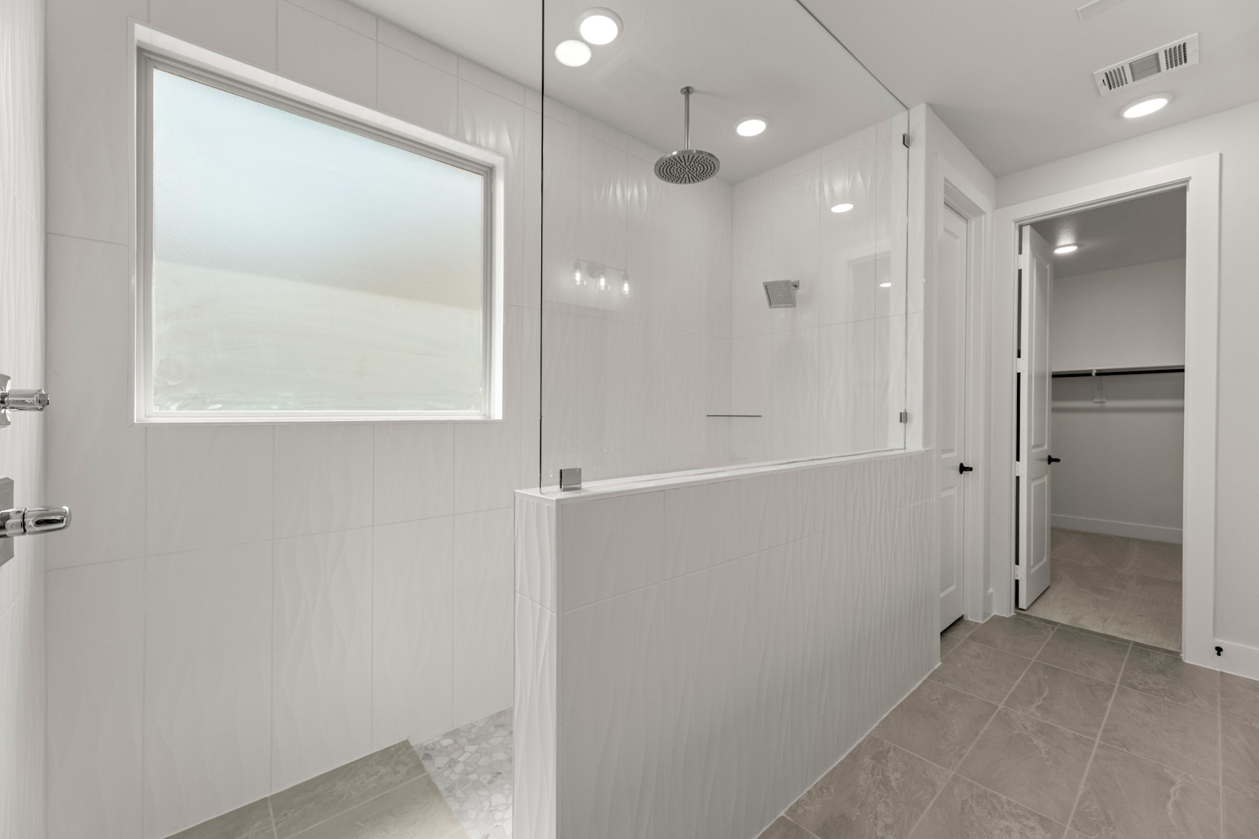 A modern, minimalist bathroom with a large window, tiled floor, and a glass shower enclosure.