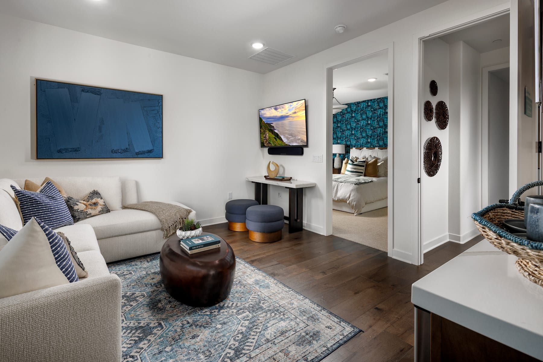 A cozy and well-decorated living room with a comfortable sofa, colorful artwork on the walls, and various decorative elements such as a side table, baskets, and a rug.
