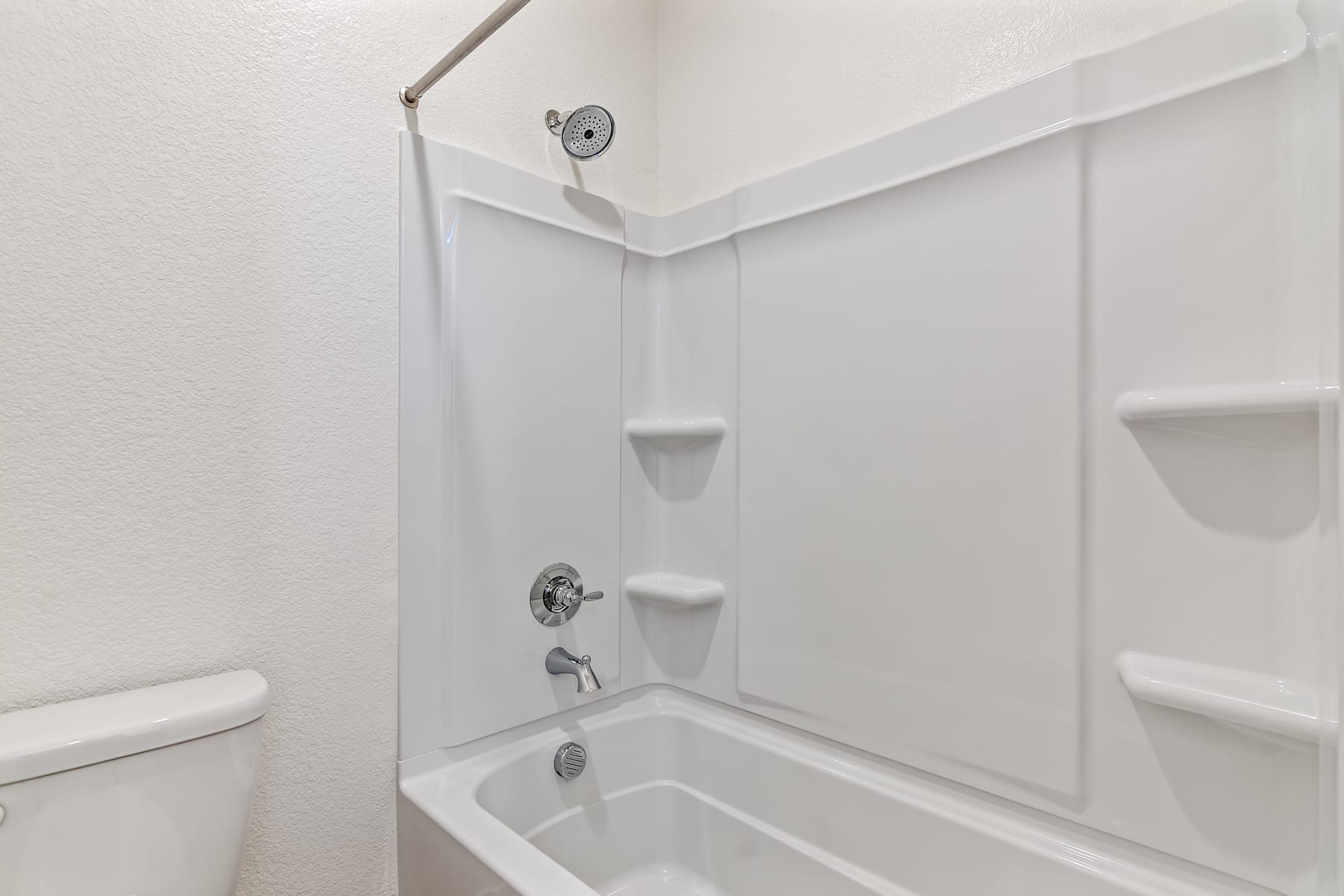 A white bathroom with a shower enclosure, a toilet, and a sink visible in the foreground.