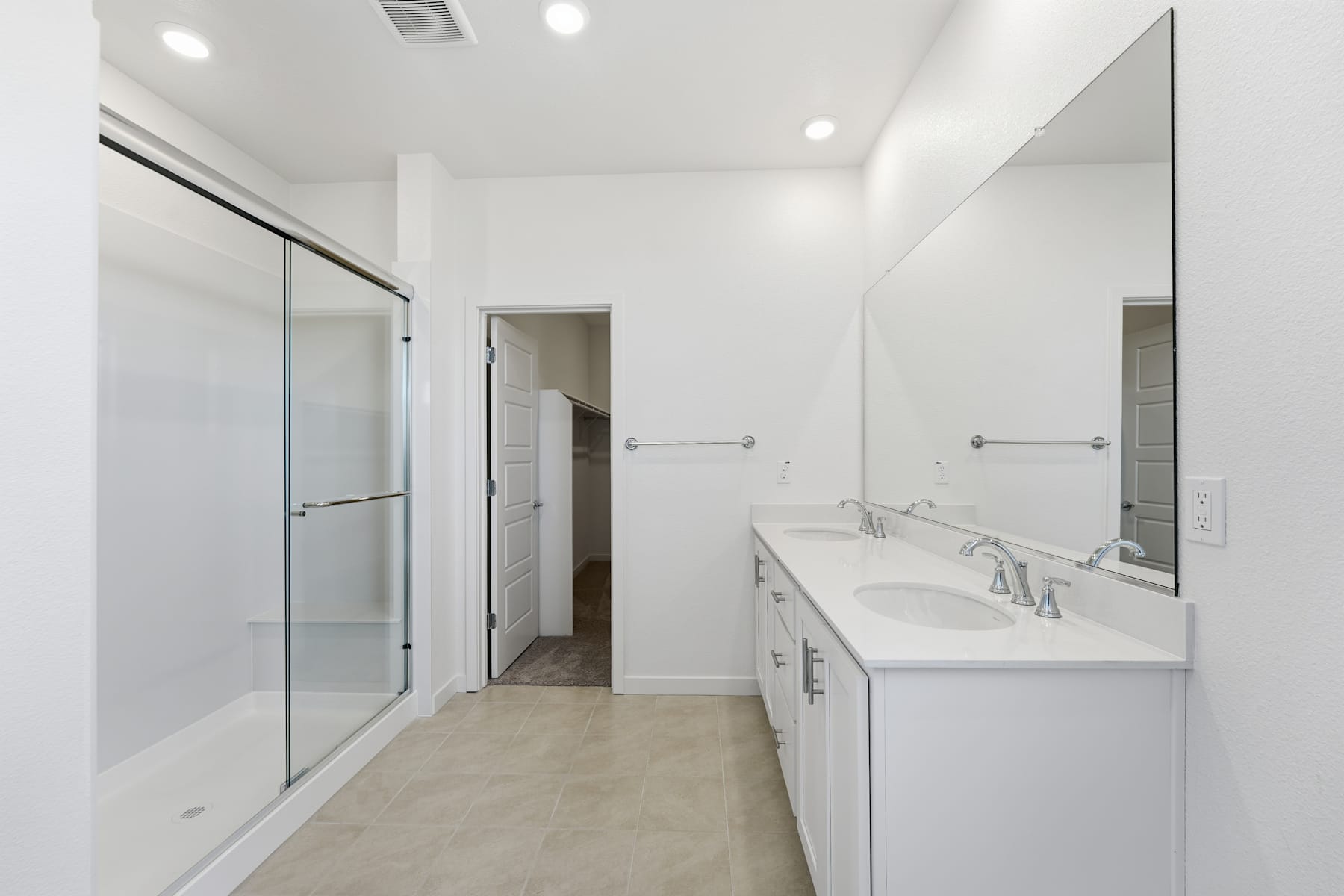 A modern, minimalist bathroom with a double vanity, a glass-enclosed shower, and a neutral color scheme.