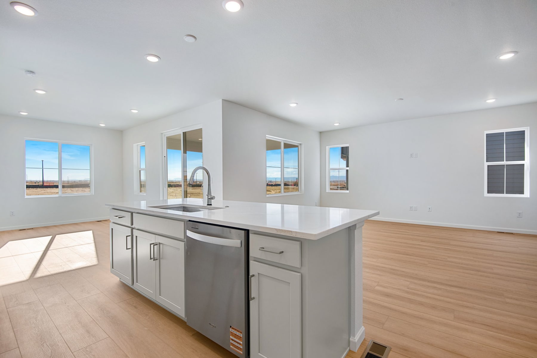 A modern, open-concept kitchen with a central island, stainless steel appliances, and large windows providing ample natural light and scenic views of the surrounding landscape.