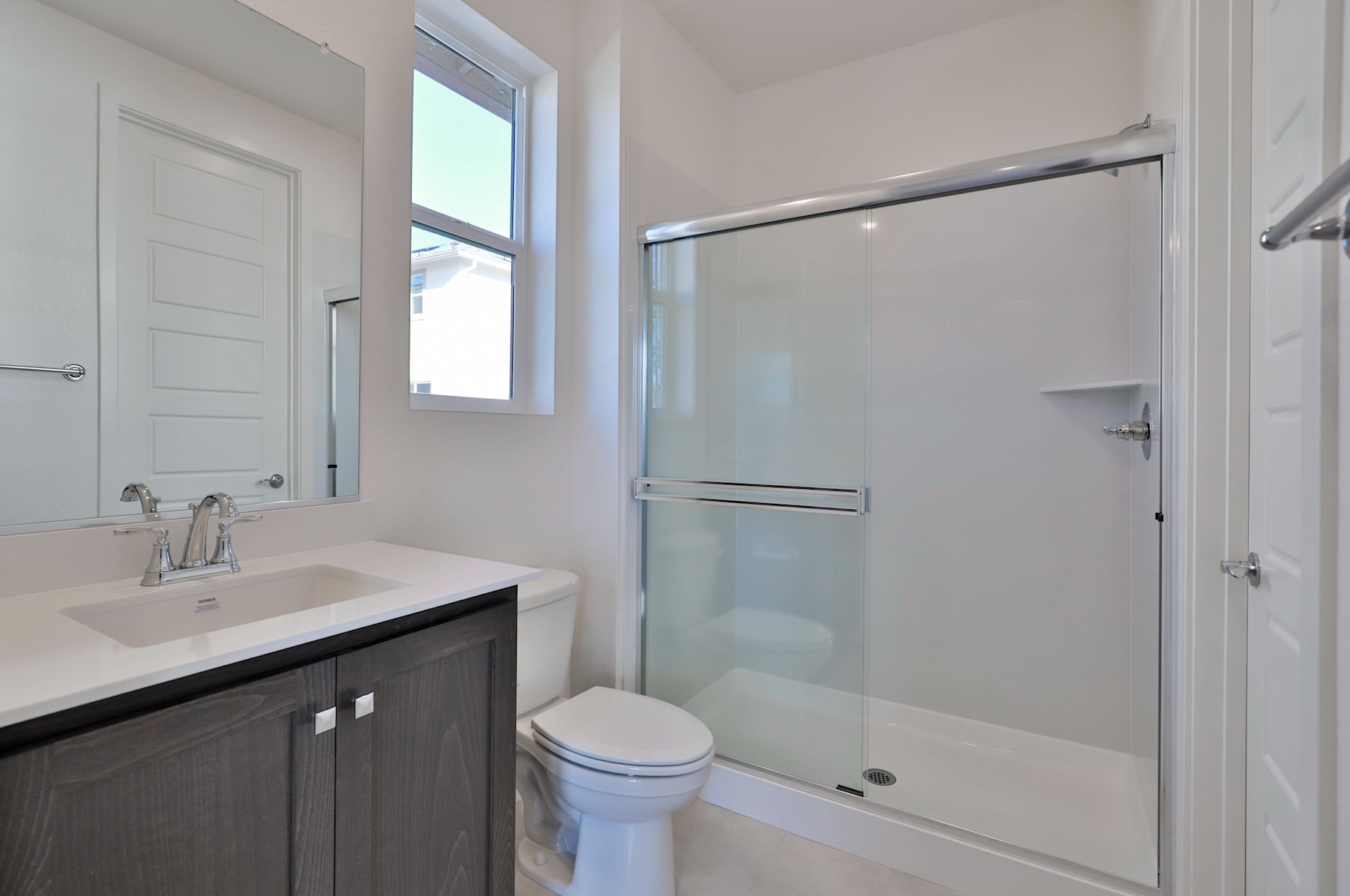 A modern bathroom with a vanity, toilet, and a glass-enclosed shower area, all in a clean and minimalist design.