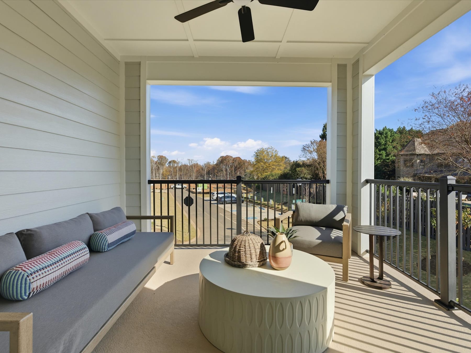 A cozy outdoor patio with comfortable seating, decorative accents, and a scenic view of the surrounding trees and sky.