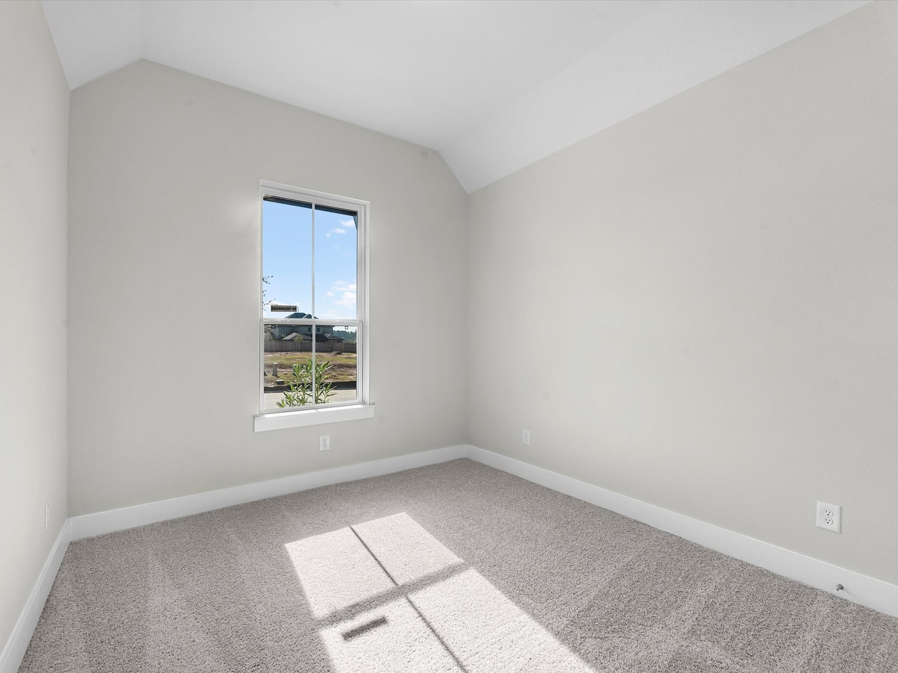 A bright, empty room with a large window overlooking a scenic outdoor landscape.