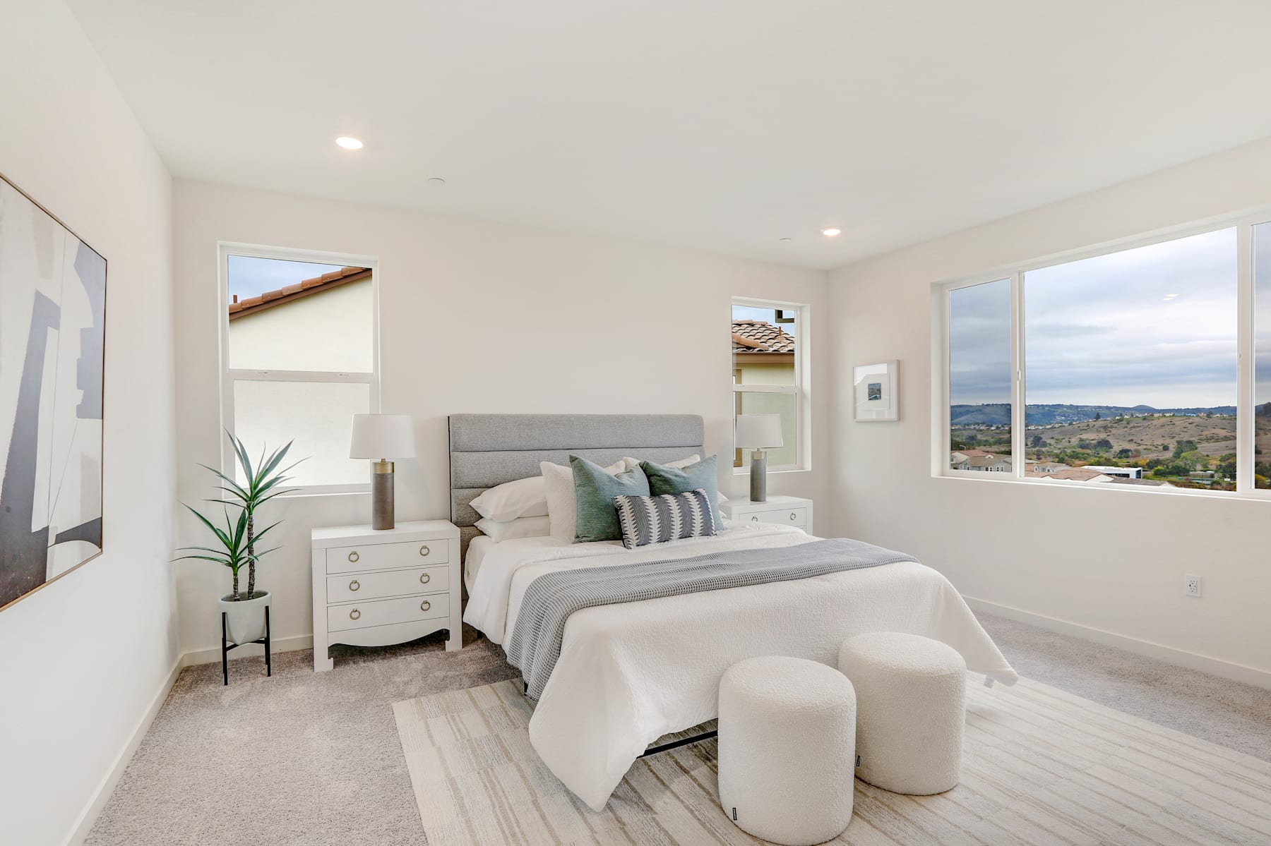 A cozy and well-designed bedroom with a large window offering a scenic view of the surrounding landscape.