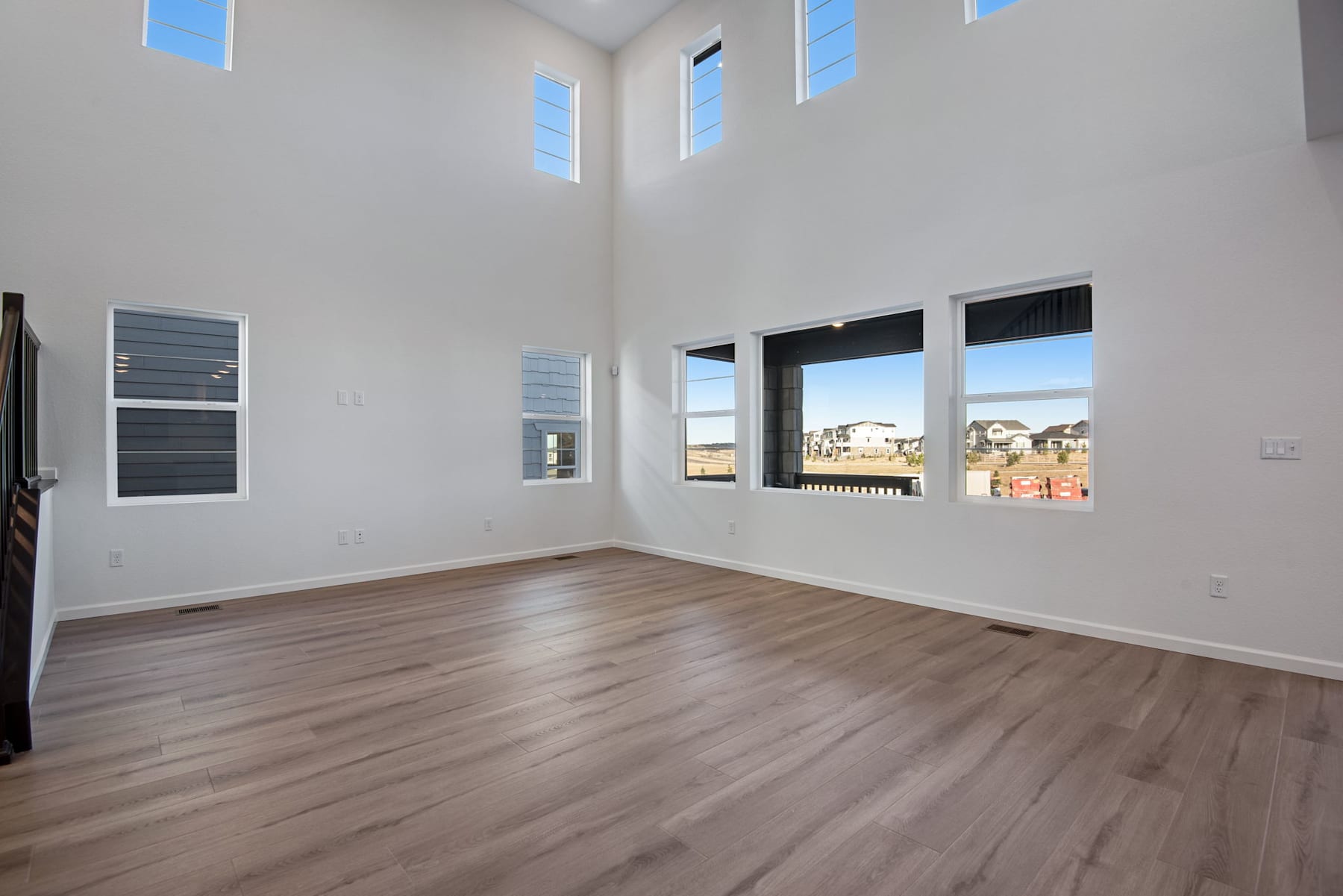A spacious, well-lit room with tall windows, hardwood floors, and a minimalist design aesthetic.