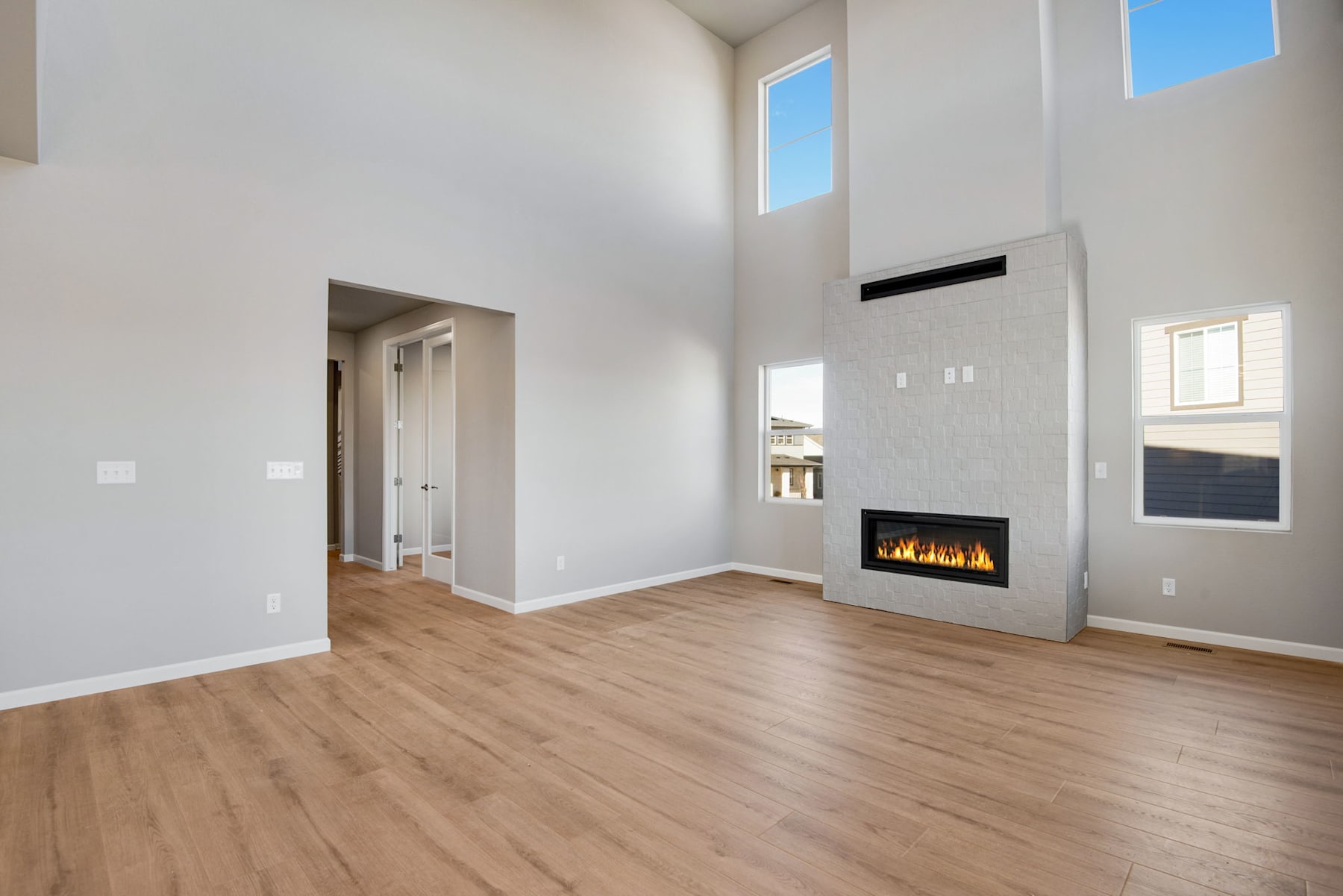 A spacious, modern living room with a fireplace, hardwood floors, and large windows allowing natural light to flood the space.