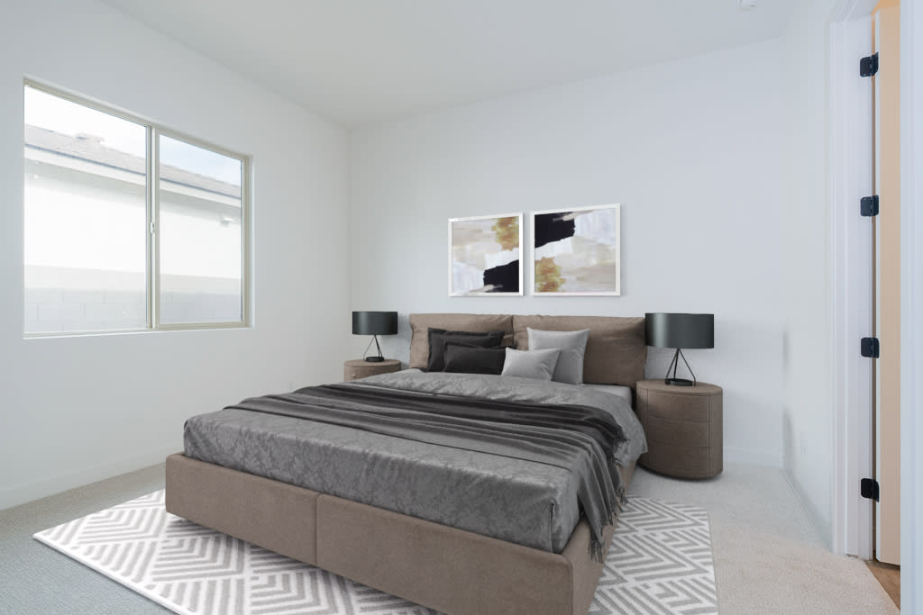 A modern and minimalist bedroom with a large bed, neutral-colored bedding, and abstract artwork on the wall. The room features large windows, allowing natural light to fill the space.