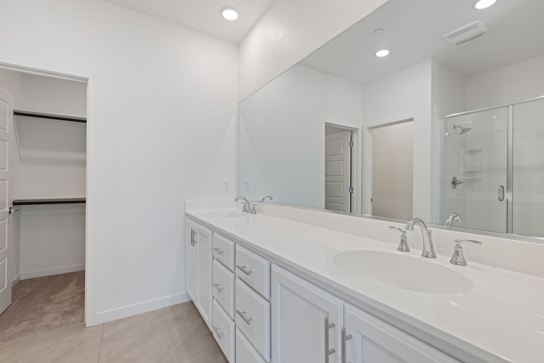 A spacious and well-lit bathroom with a large vanity, double sinks, and a glass-enclosed shower area.
