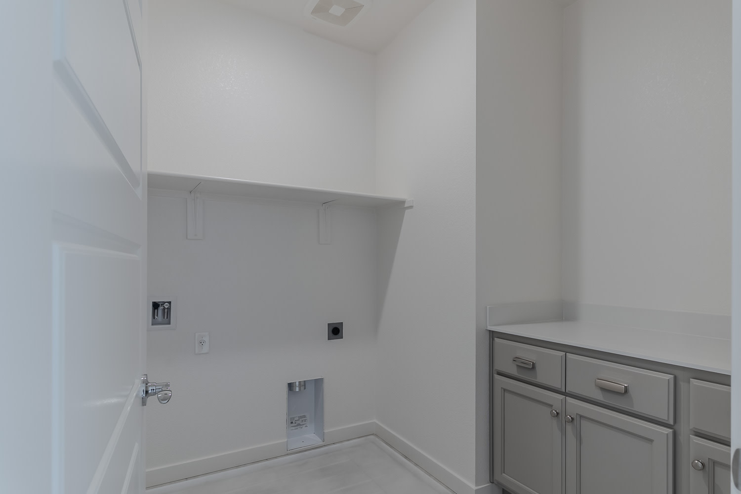 A minimalist bathroom interior with white walls, a cabinet with drawers, and a recessed lighting fixture on the ceiling.
